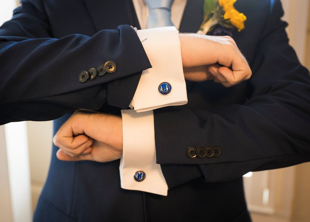 Close-up detail shot of formal suit cuffs with dark blue buttons.
