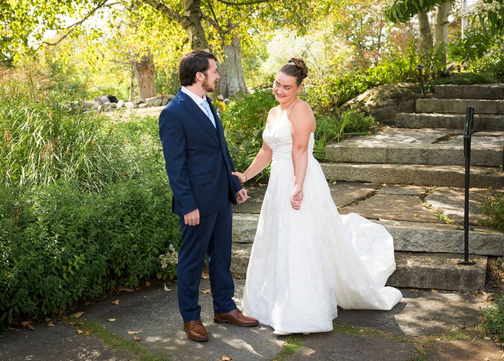 Wedding couple walks along stone path in garden during outdoor photo session.