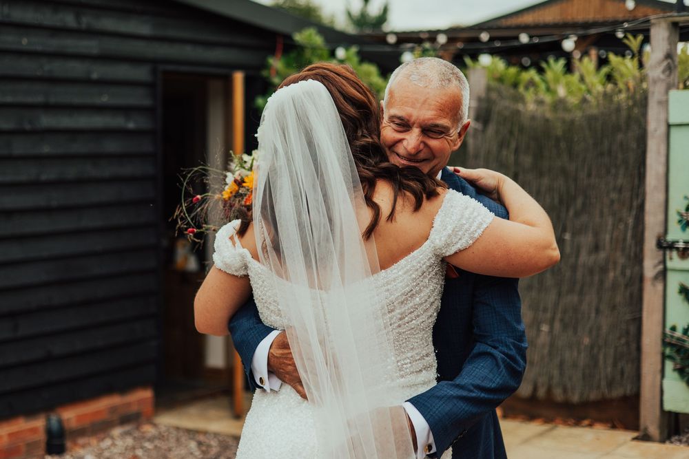 A bride and groom share an intimate embrace in a garden setting during their wedding celebration.