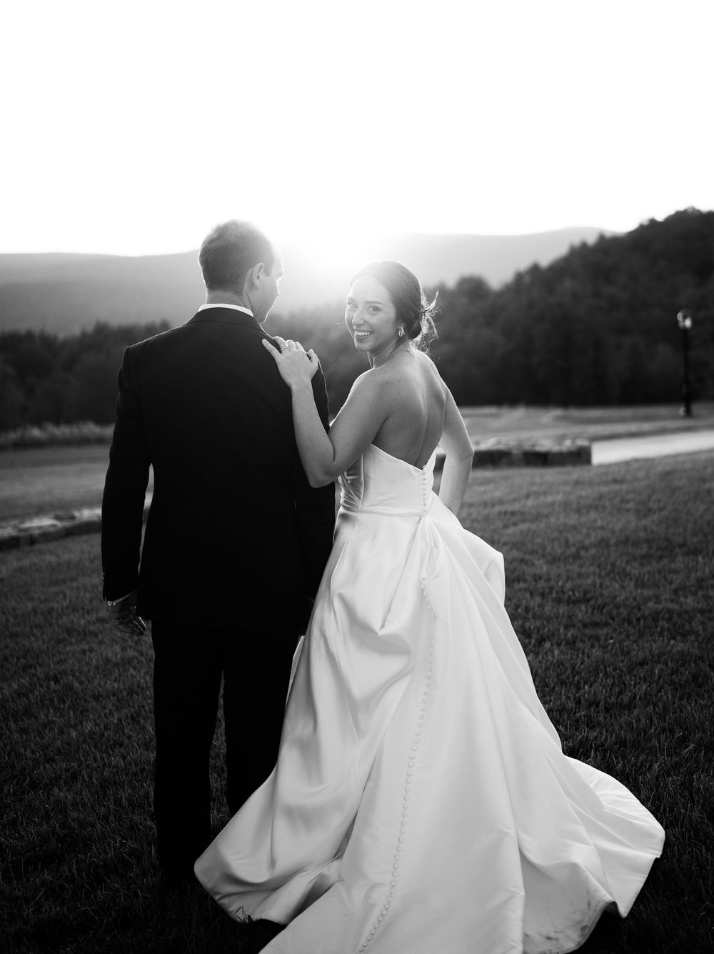 Romantic black and white portraits of newlyweds in an open field at sunset.