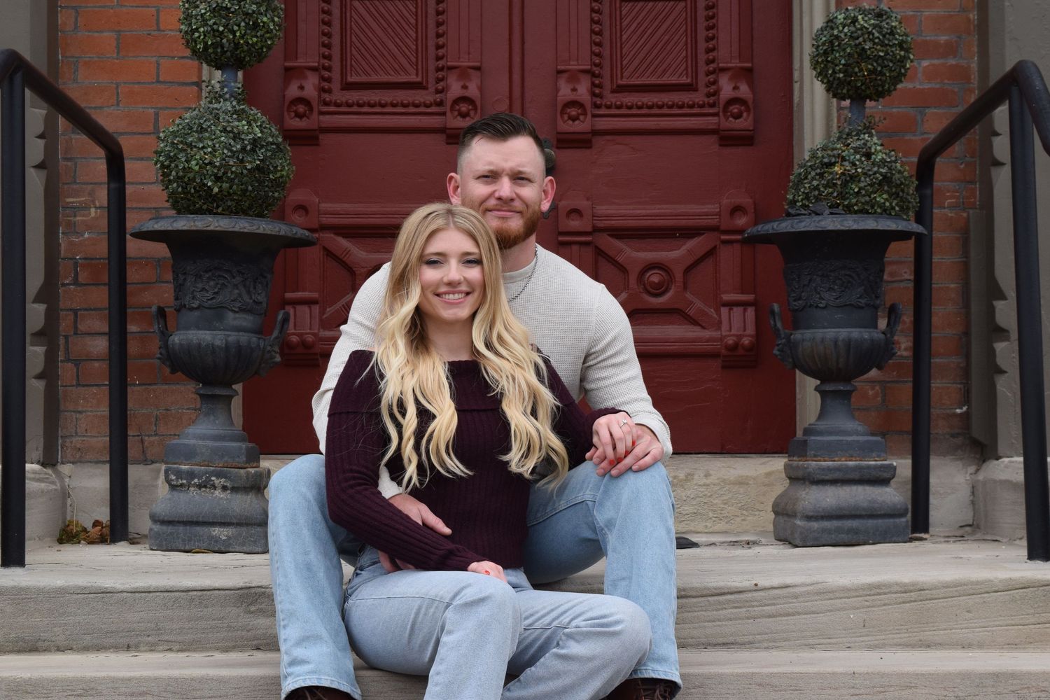 Couple sitting together on the steps of a mansion