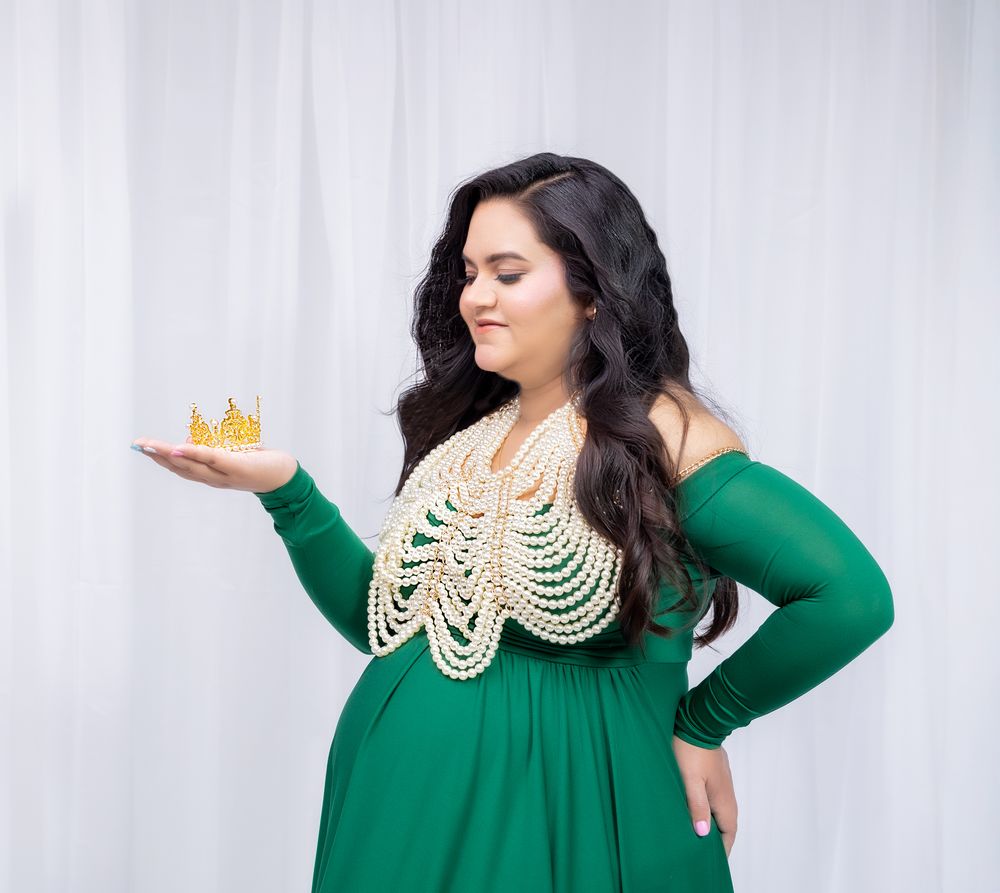 Elegant emerald dress with ornate cream-colored neckpiece photographed in studio with white background.