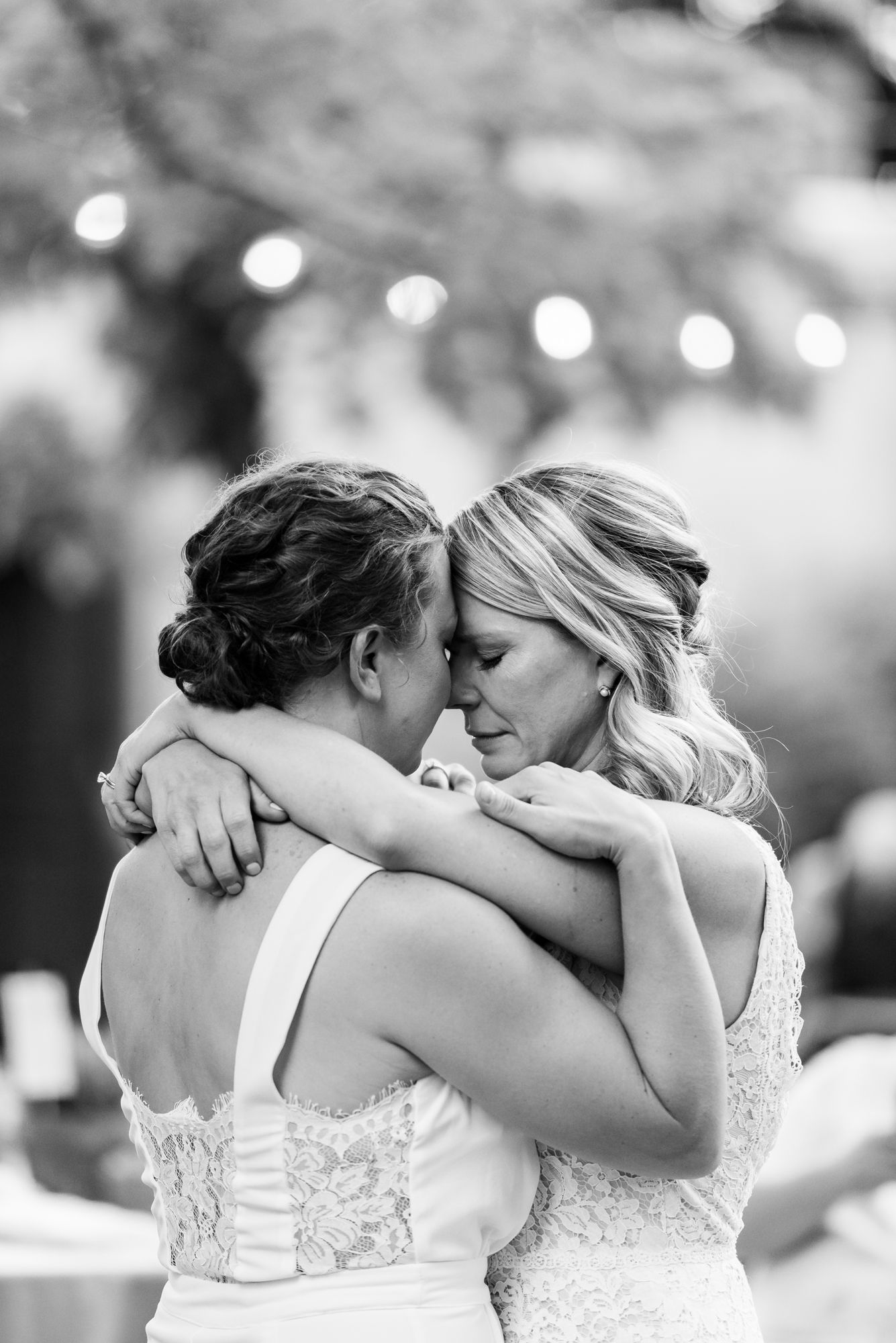 Intimate black and white portrait of two brides embracing during an emotional wedding moment.