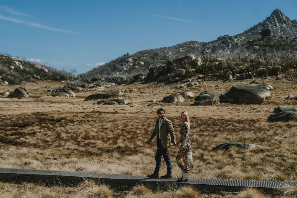 A hiker traverses a rocky mountain terrain under blue skies during an outdoor adventure.