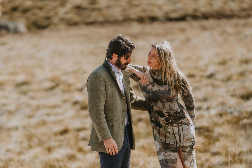A couple shares a romantic moment in a desert landscape wearing brown and white tones during an engagement photoshoot.