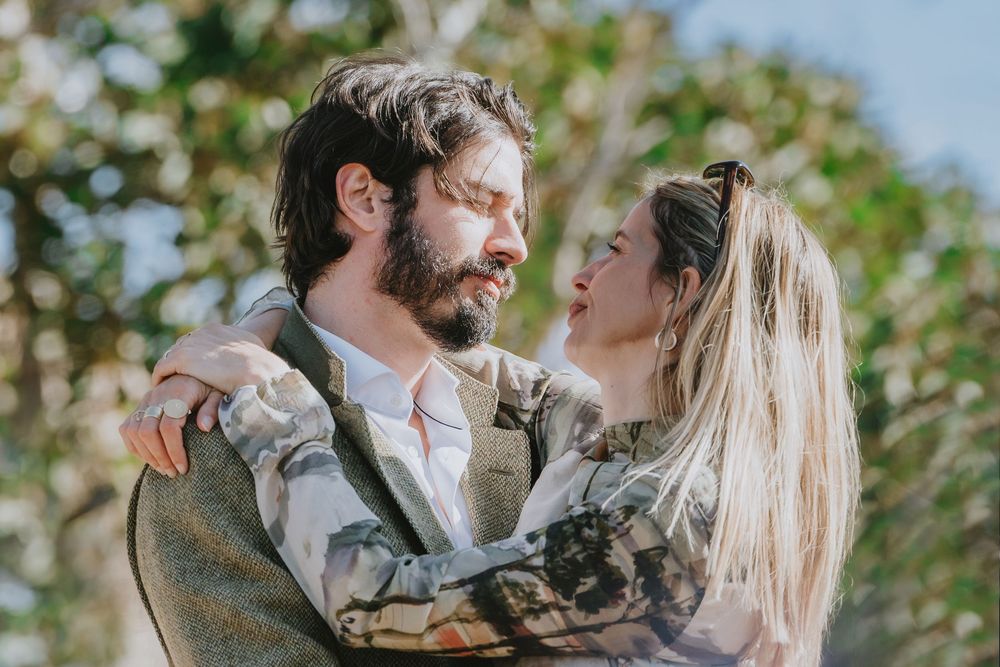 A couple in rustic outdoor attire sharing romantic moments against a natural green background.