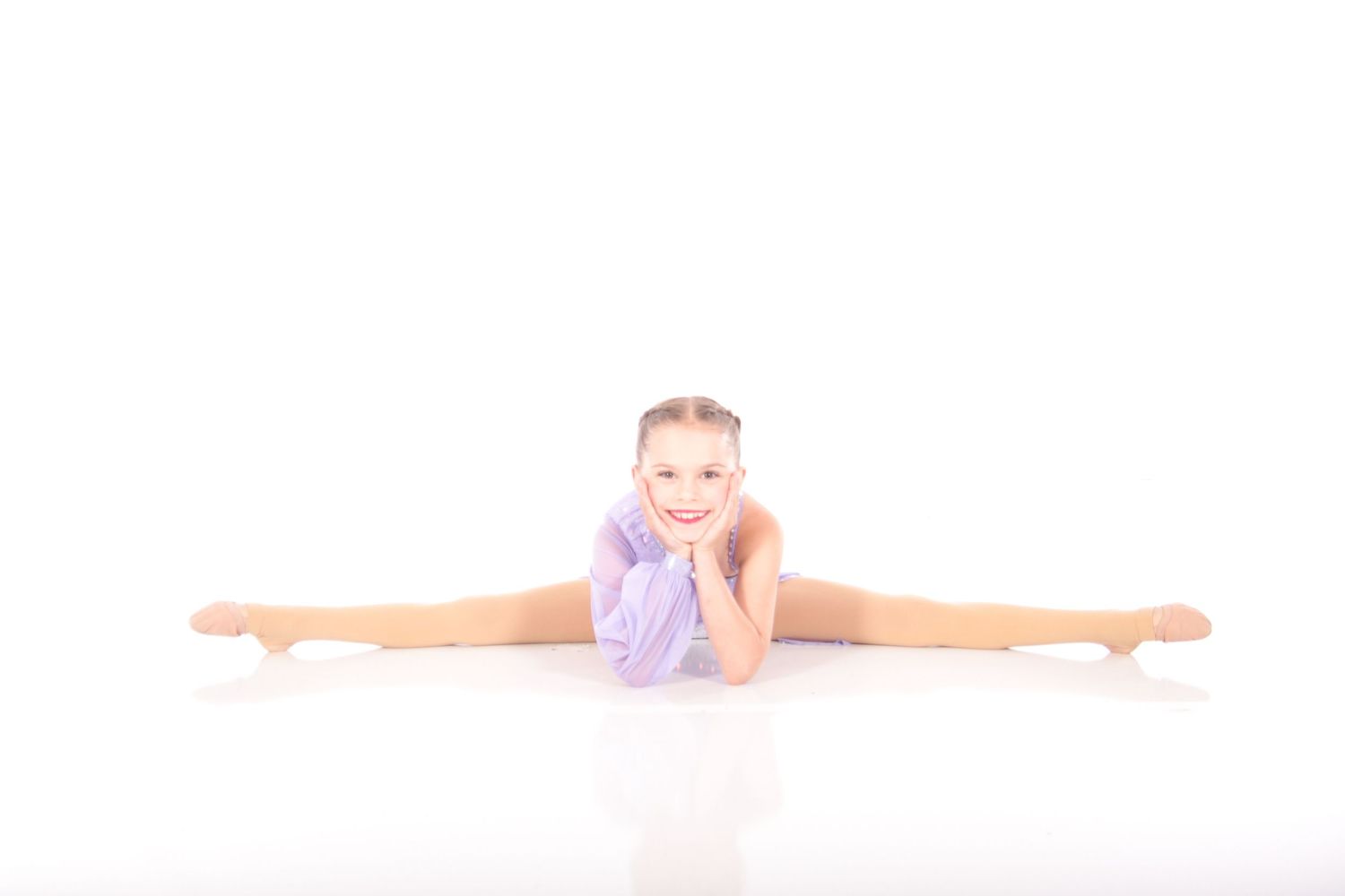Gymnast in purple leotard performs perfect splits position on white background.