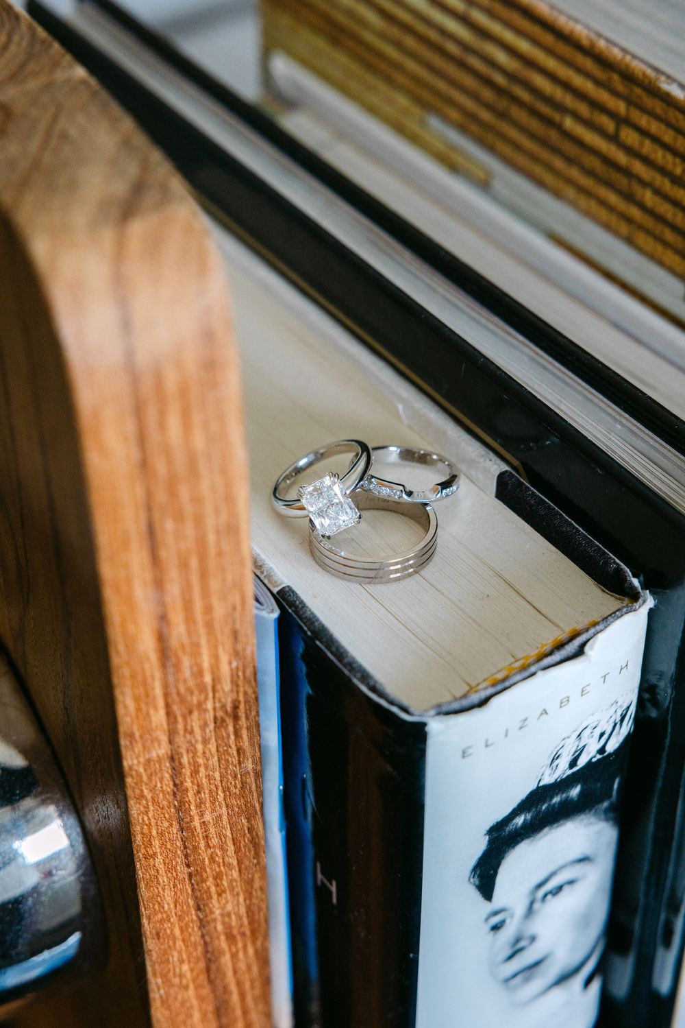 Diamond engagement ring rests elegantly on top of a vintage book spine against a wooden surface.
