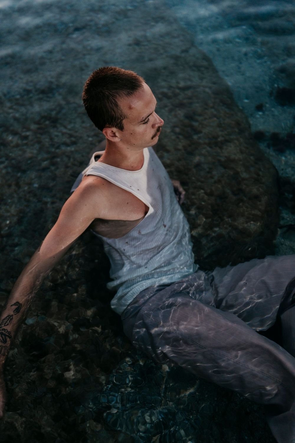 Figure in wet white clothing moving through dark waters.