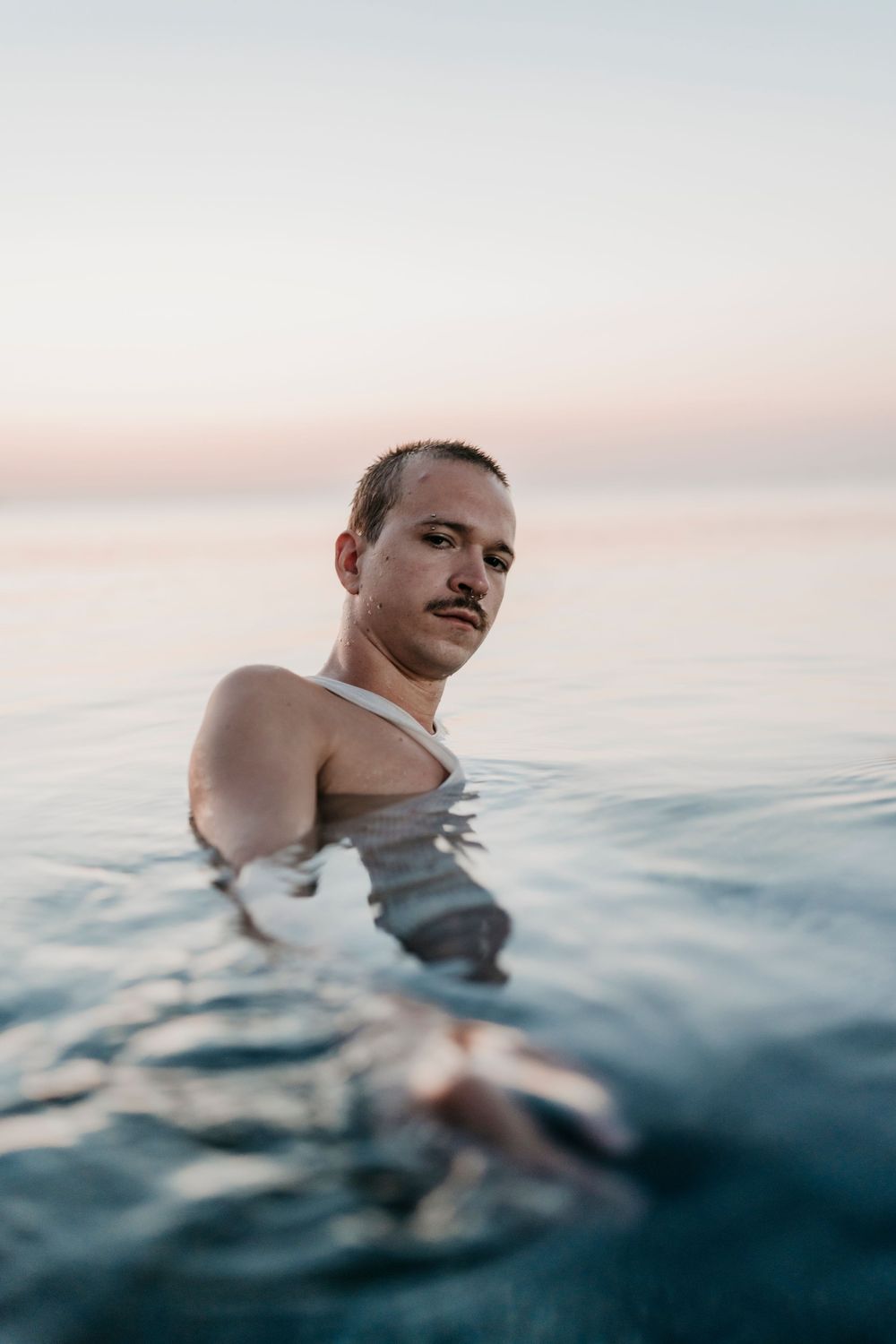 Person floating in calm ocean waters during sunset.
