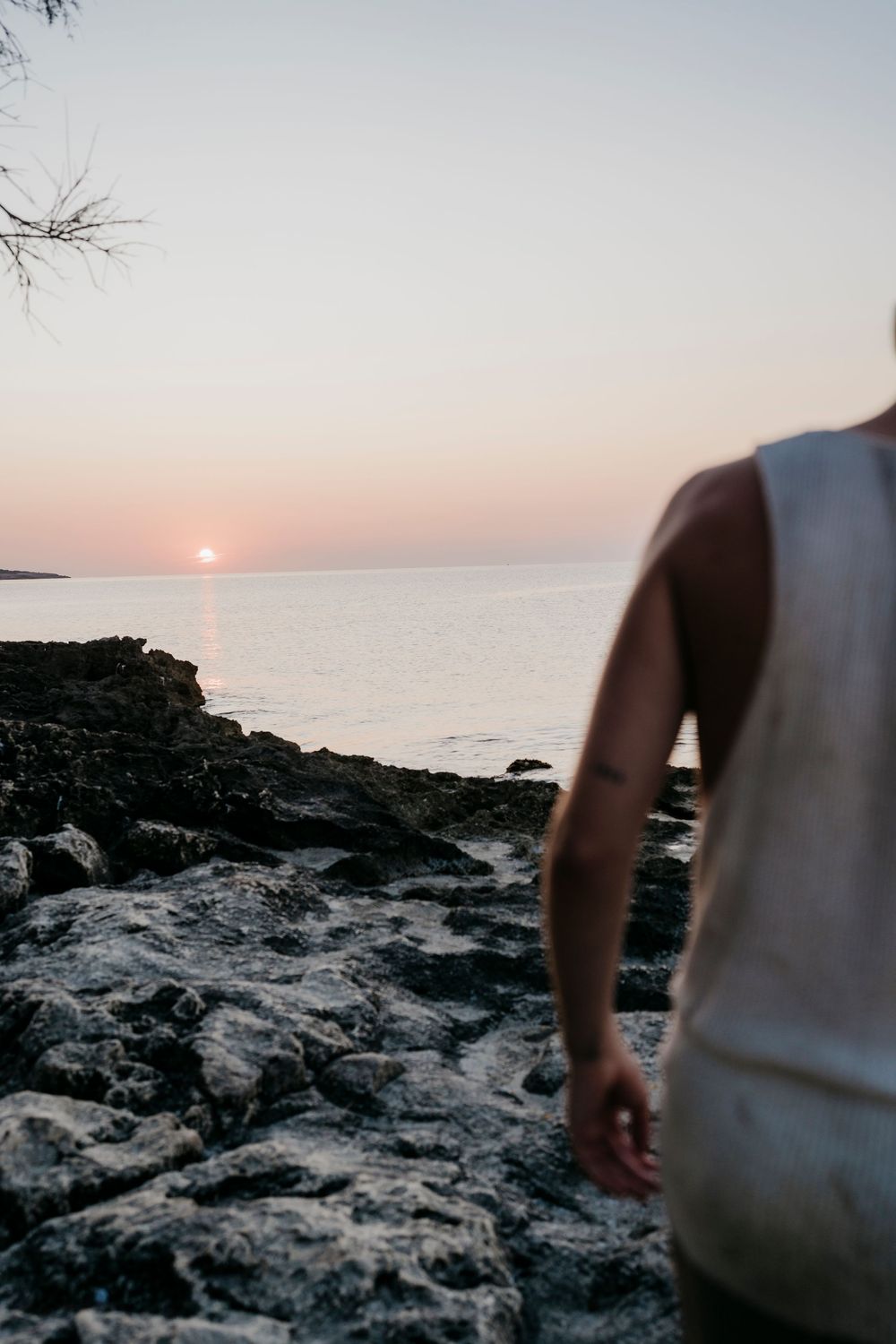 Rocky coastal landscape at sunset with silhouetted figure in foreground.