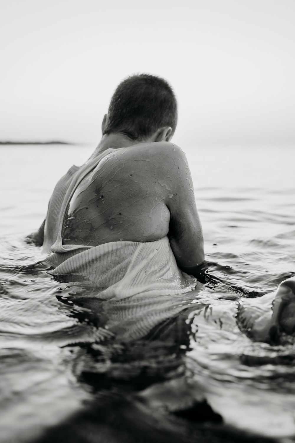 Person floating in ocean water wearing light colored clothing.