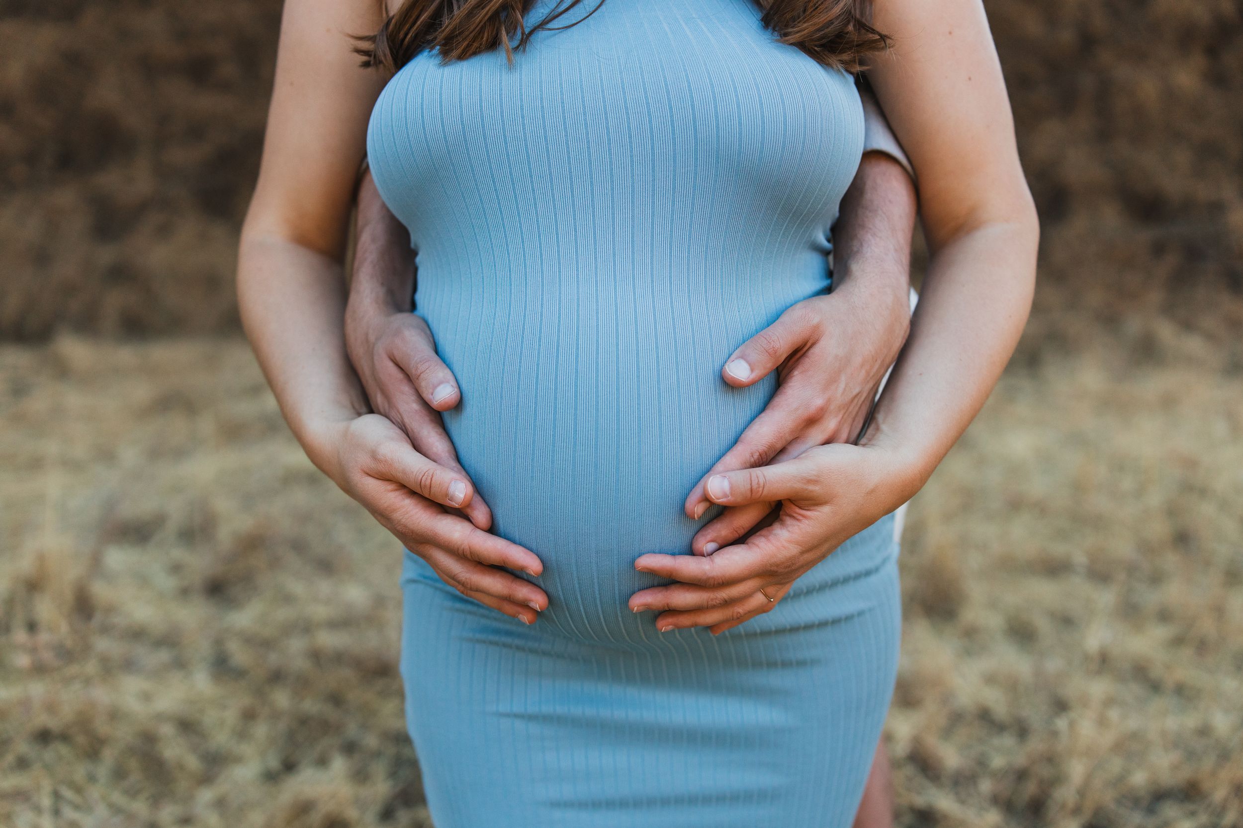 Close-up sequence of a pregnant belly in a light blue dress showing progression from different angles of pregnancy.