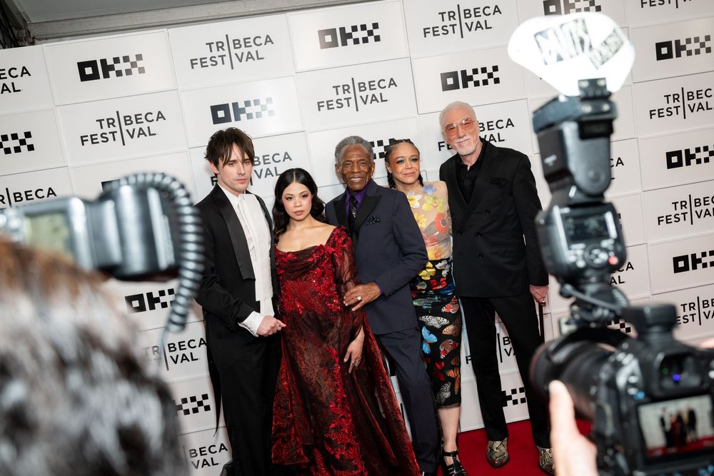 Five guests pose on the red carpet at the Tribeca Festival, smiling for cameras at the prestigious film event.