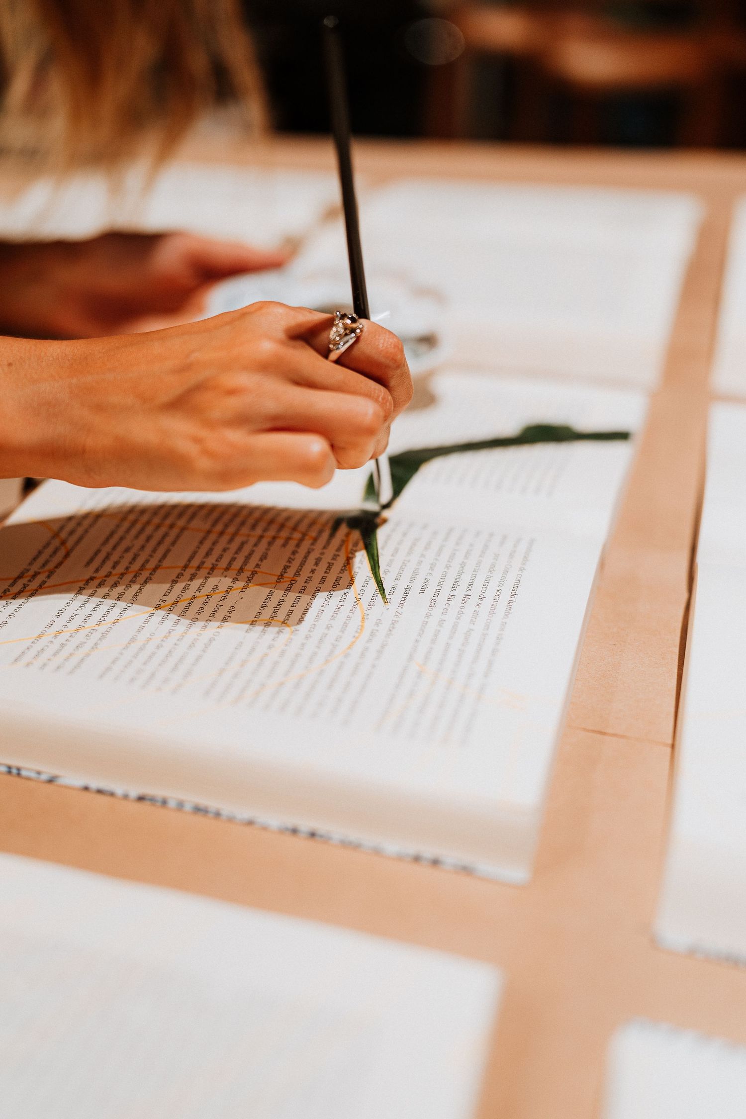 Hand with ring holding pen while writing in an open book.