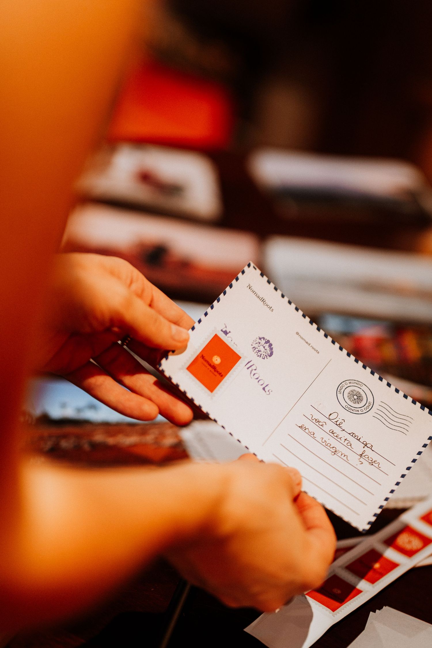 Hands holding vintage-style letters or envelopes against warm orange background.
