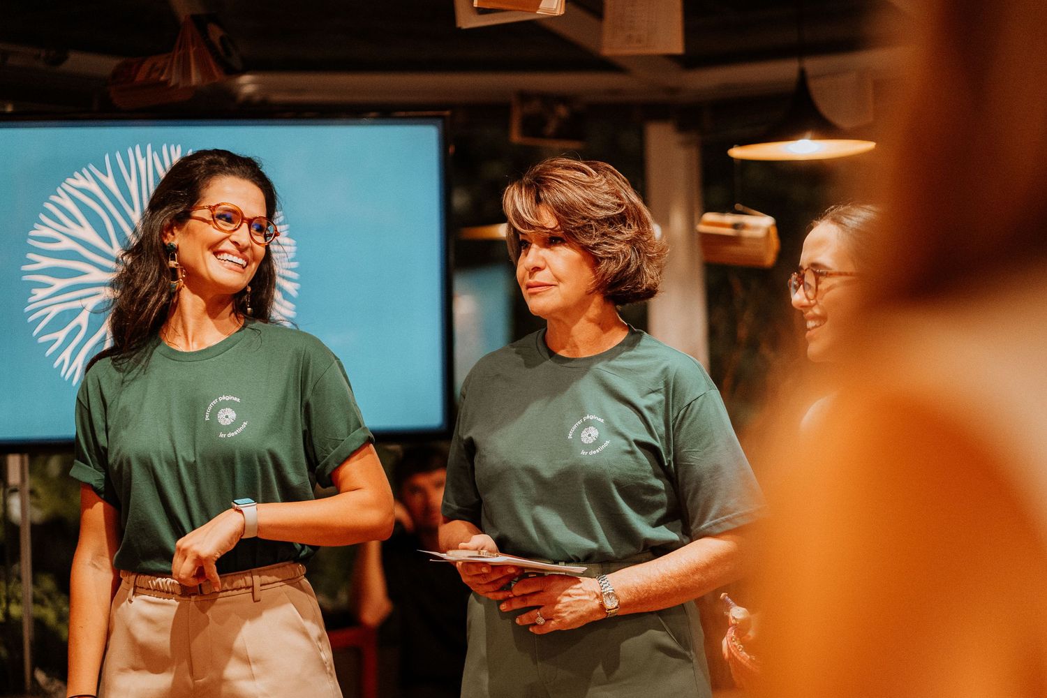 Group wearing matching green shirts gathered in indoor space.