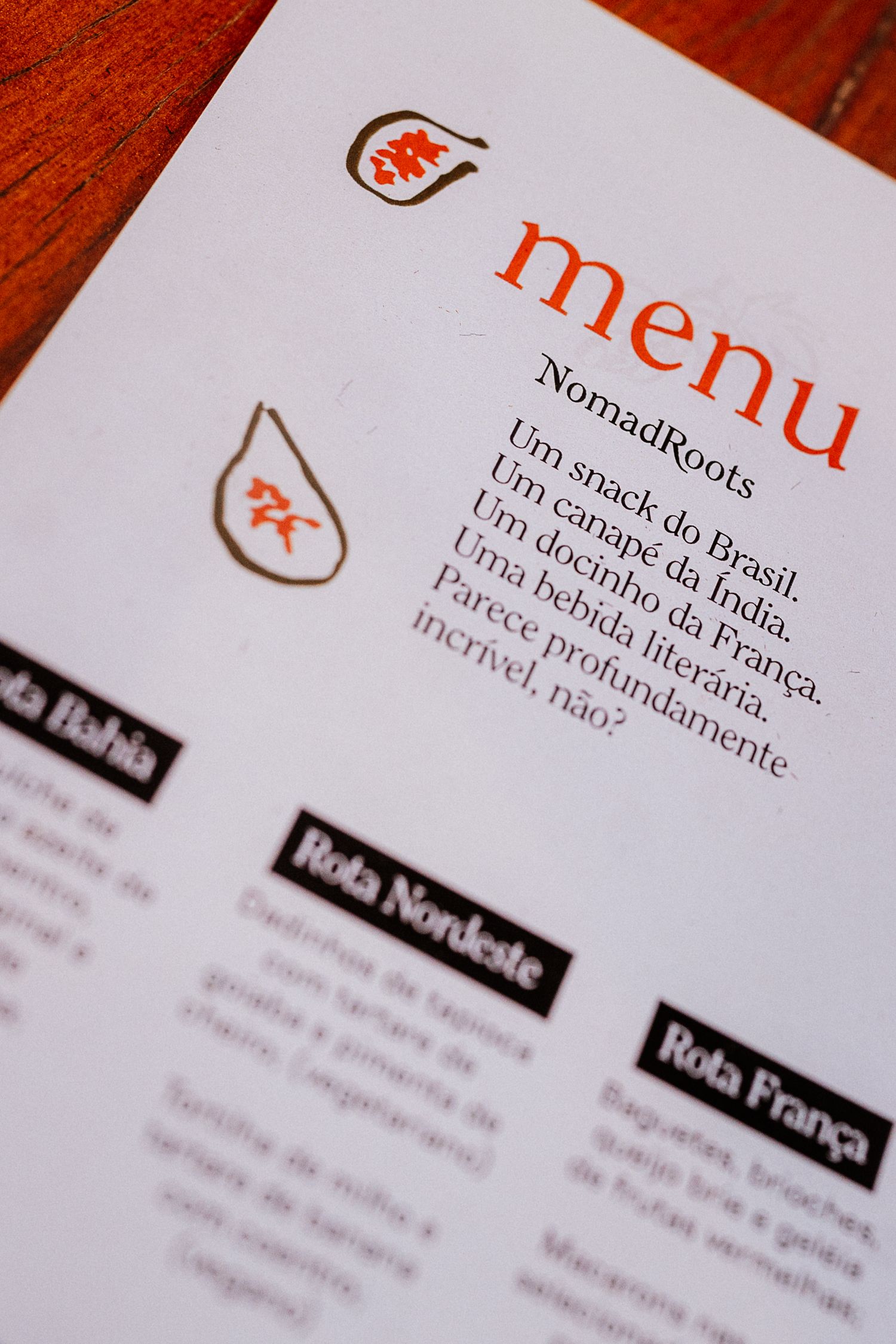 Close-up of a restaurant menu with NomadRoots branding and text in Portuguese.