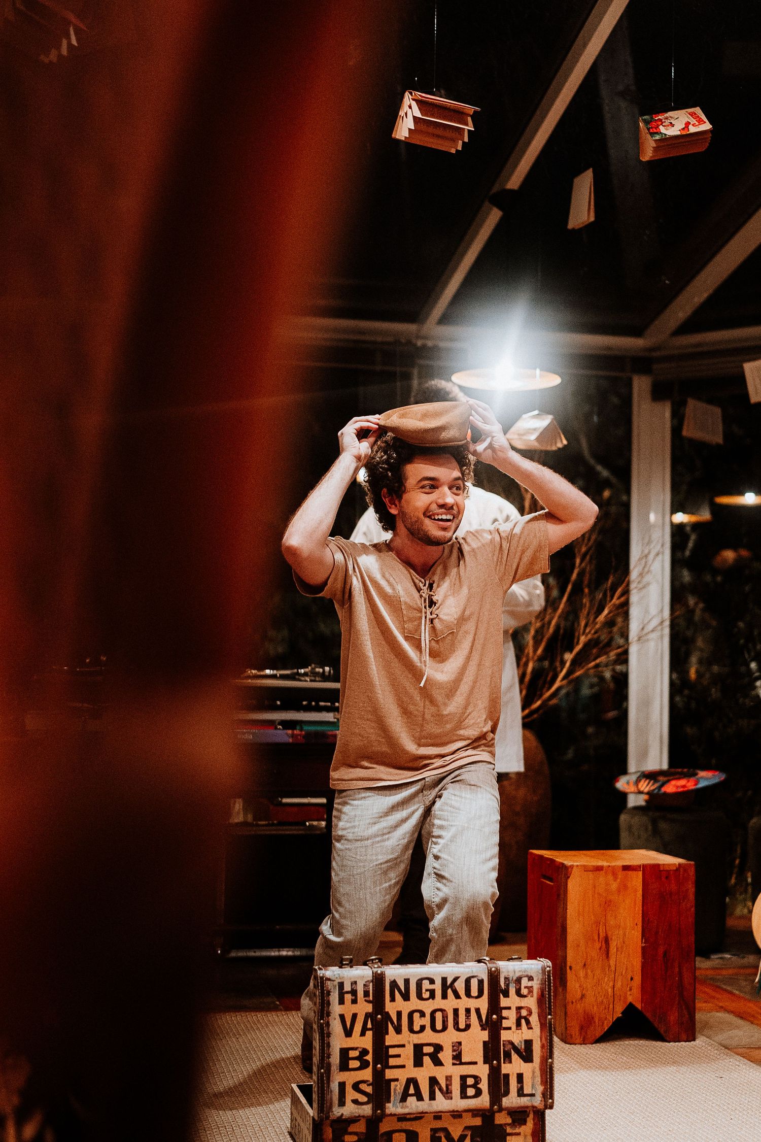 Performer expressing joy while standing on a wooden box with city names.