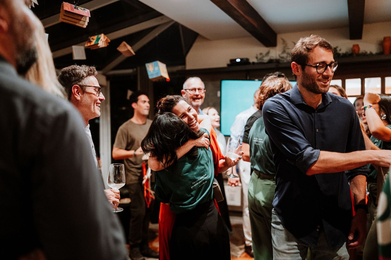 Group of people engaged in animated conversation at an indoor social event.