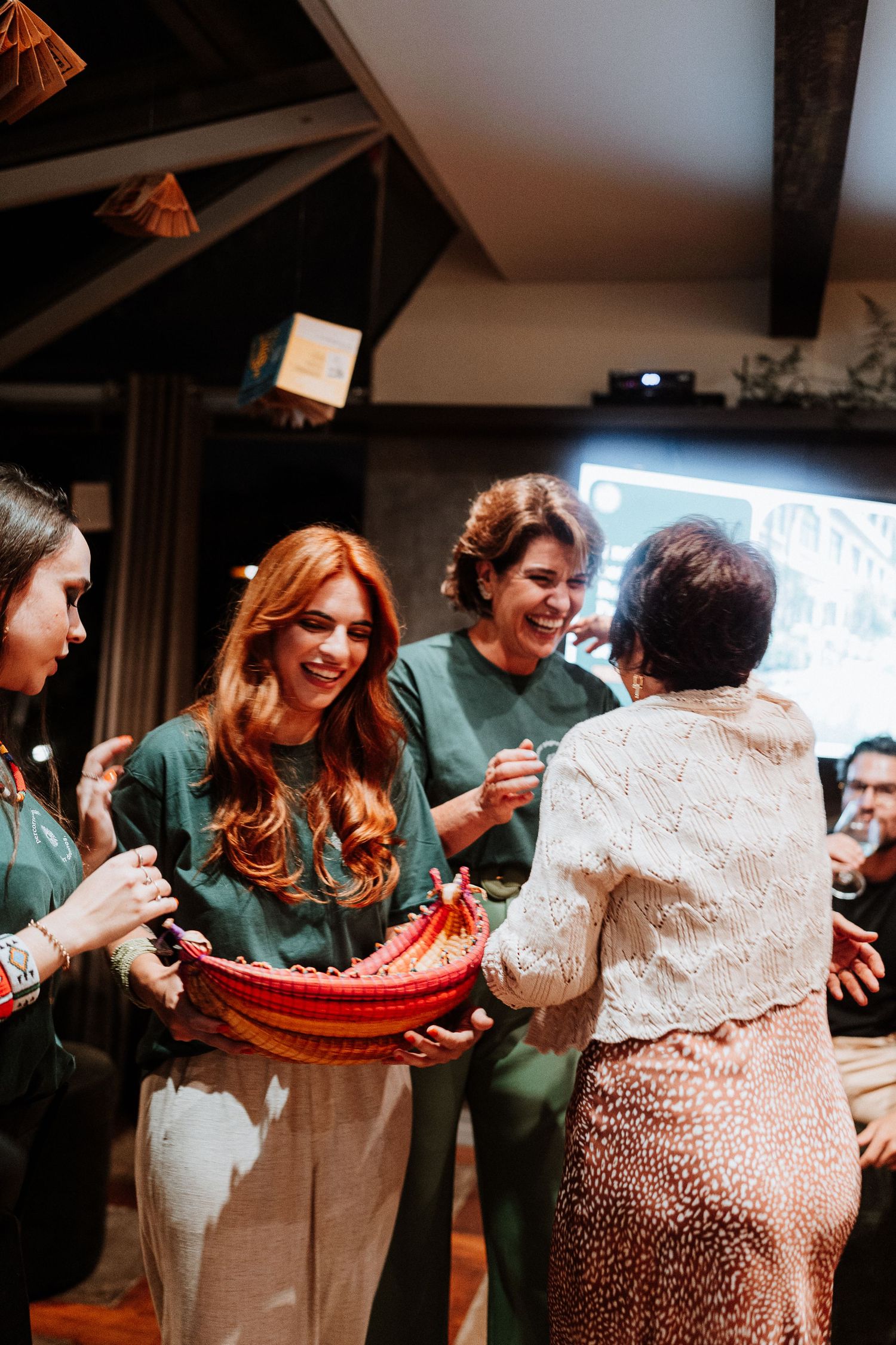 Group celebrating together in emerald green outfits while exchanging a colorful gift.
