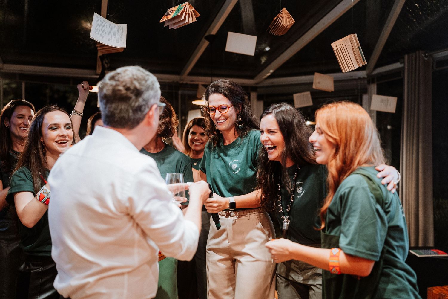 Celebratory moment at an indoor event with people in matching green shirts interacting enthusiastically.