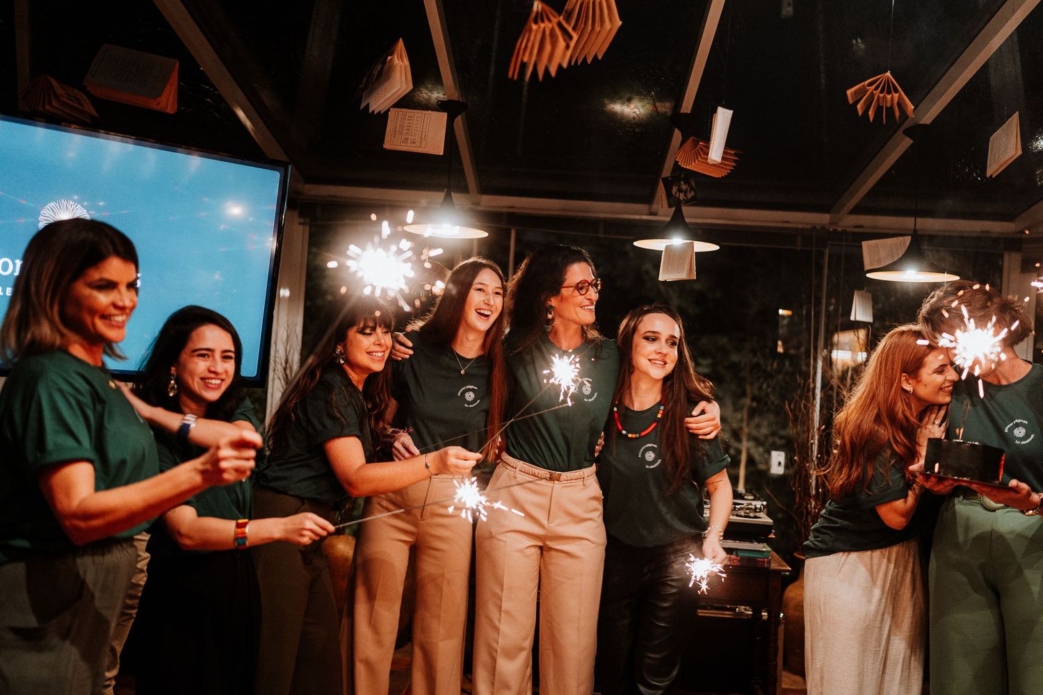 People in coordinated outfits holding sparklers during an indoor celebration.