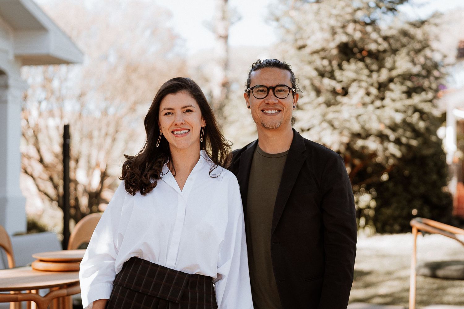 Two people standing together outdoors in casual business attire.