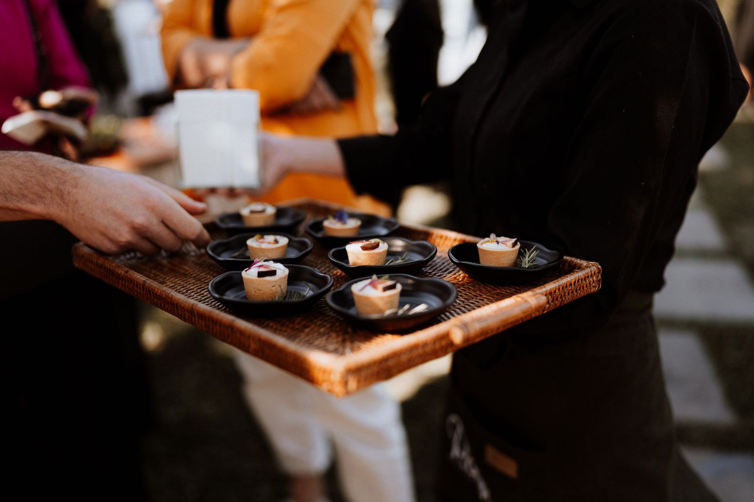 A wooden tray of elegant appetizers or desserts being served at an upscale event.