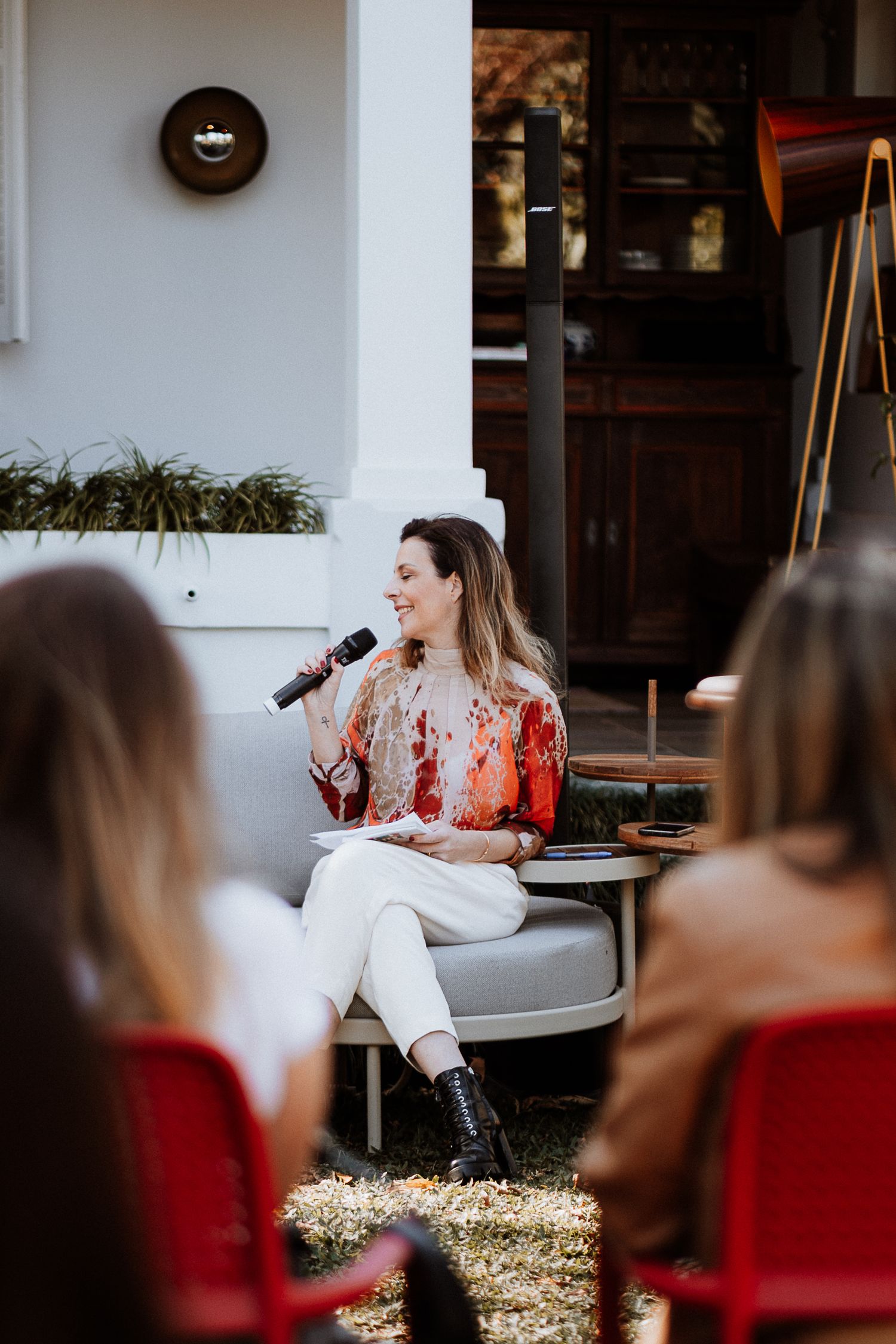 An intimate outdoor event with a speaker seated on a white couch.
