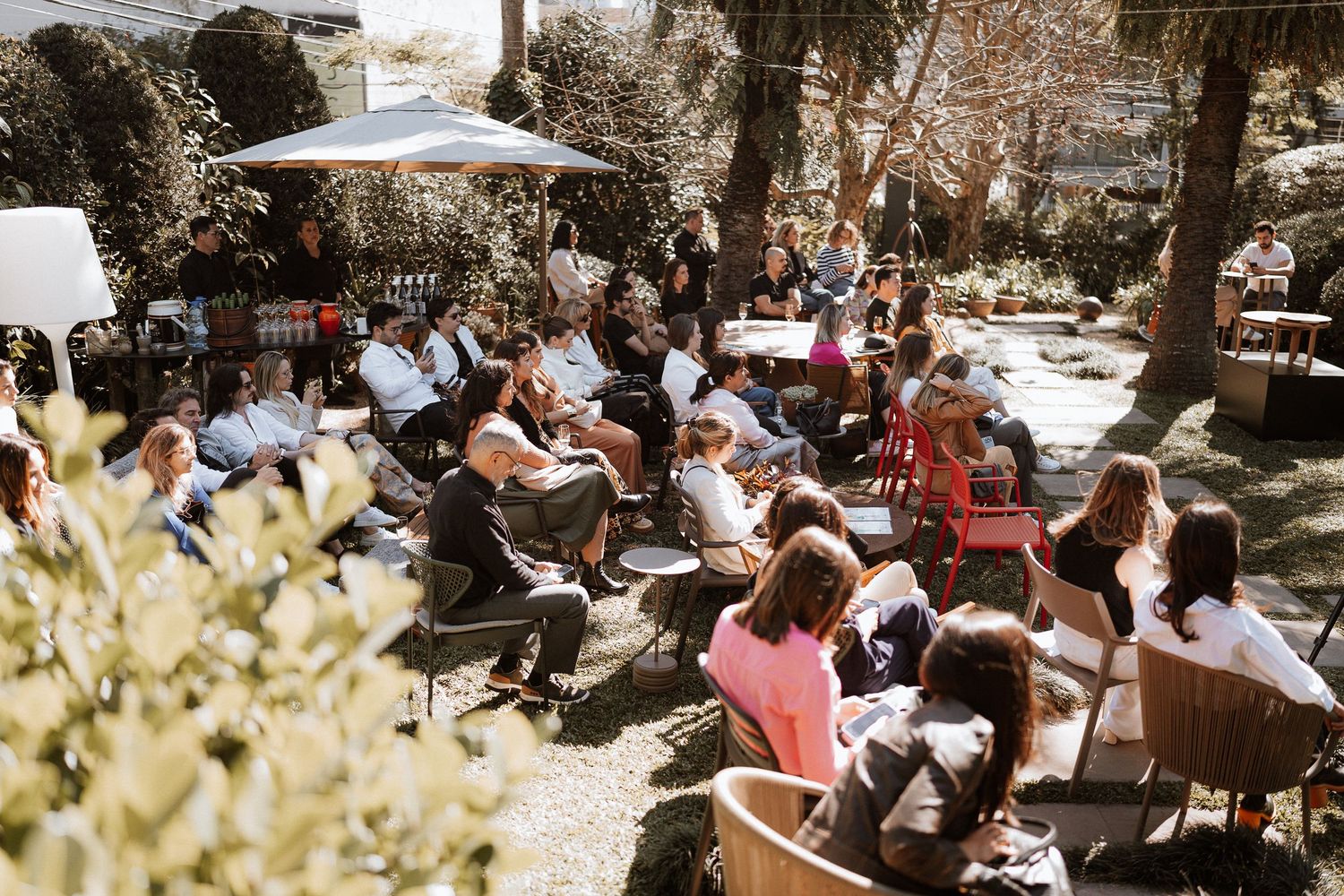 Guests seated in outdoor chairs during a sunny daytime event.