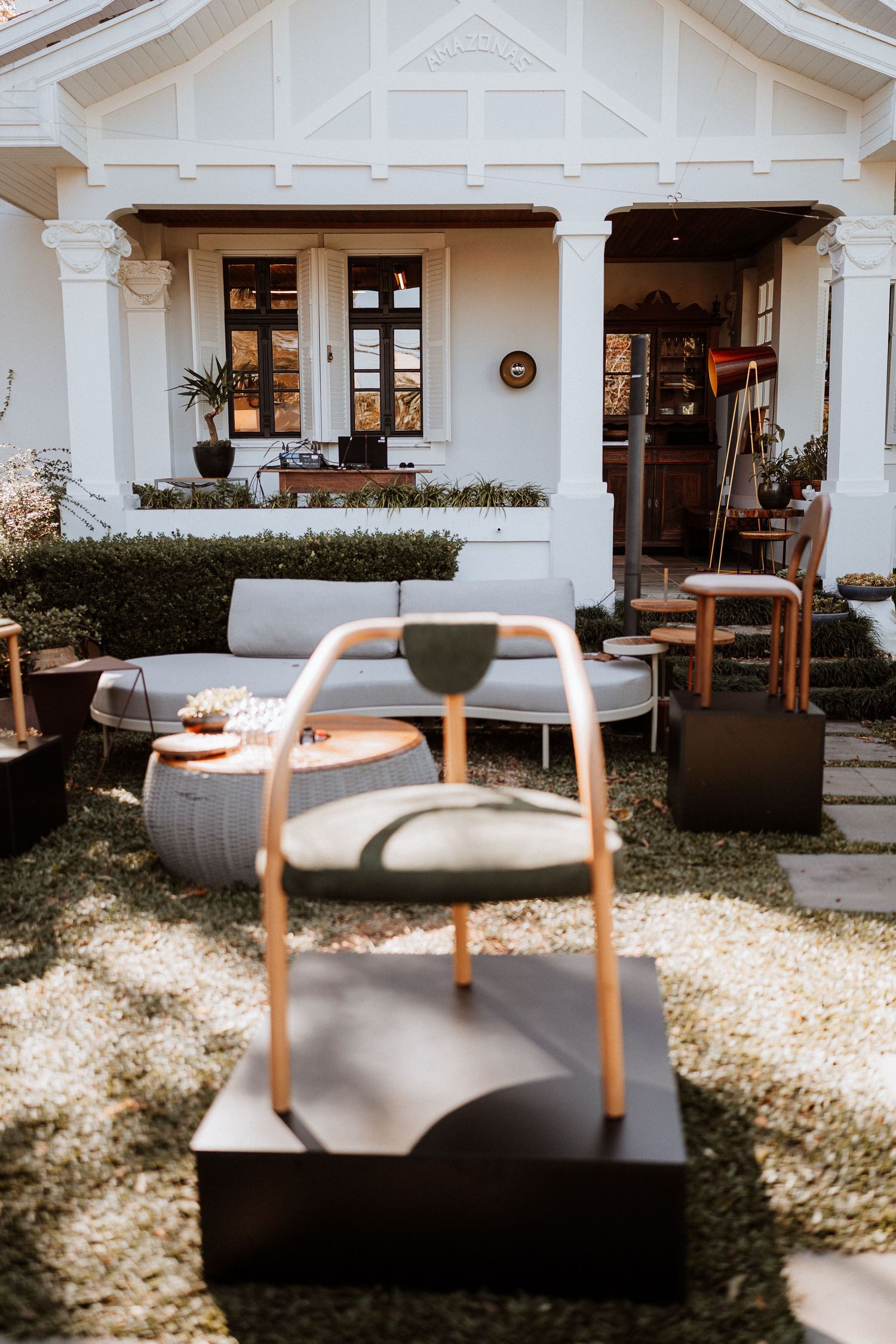 Modern outdoor seating area with gray chairs and wooden accents in front of a white house.