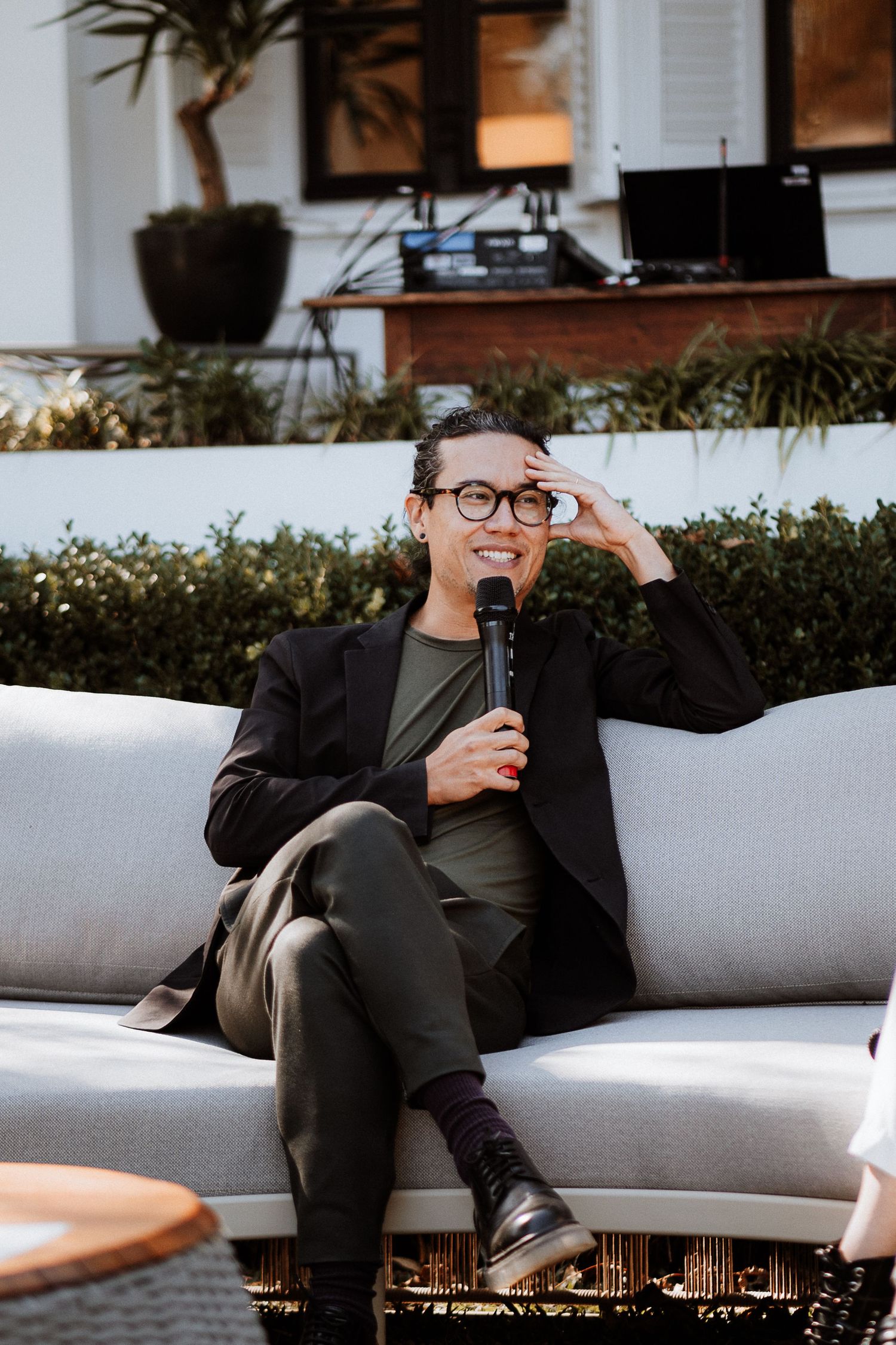 A speaker relaxing on a gray sofa during an outdoor event.