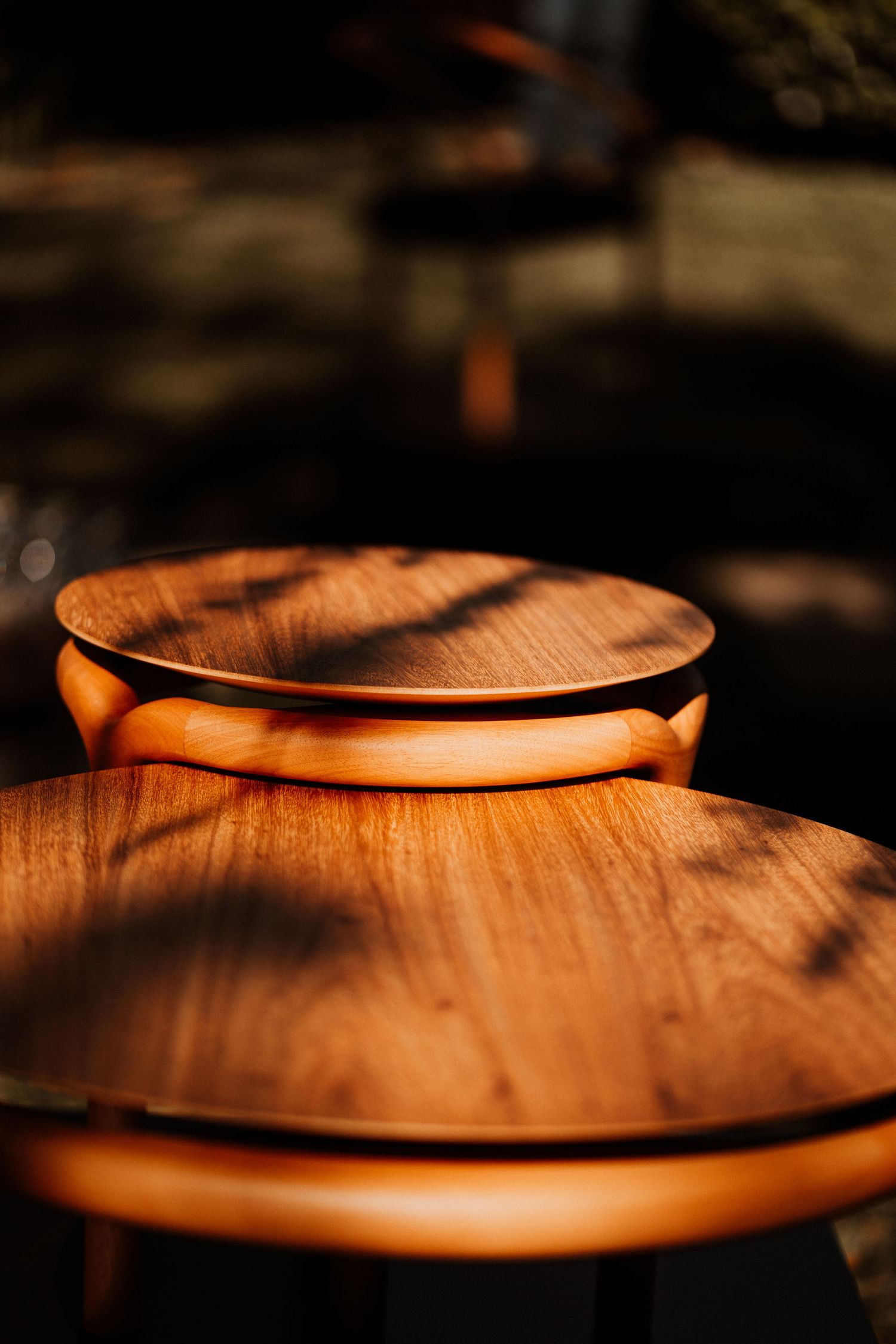Wooden circular plates catching warm sunlight and casting shadows on a textured surface.