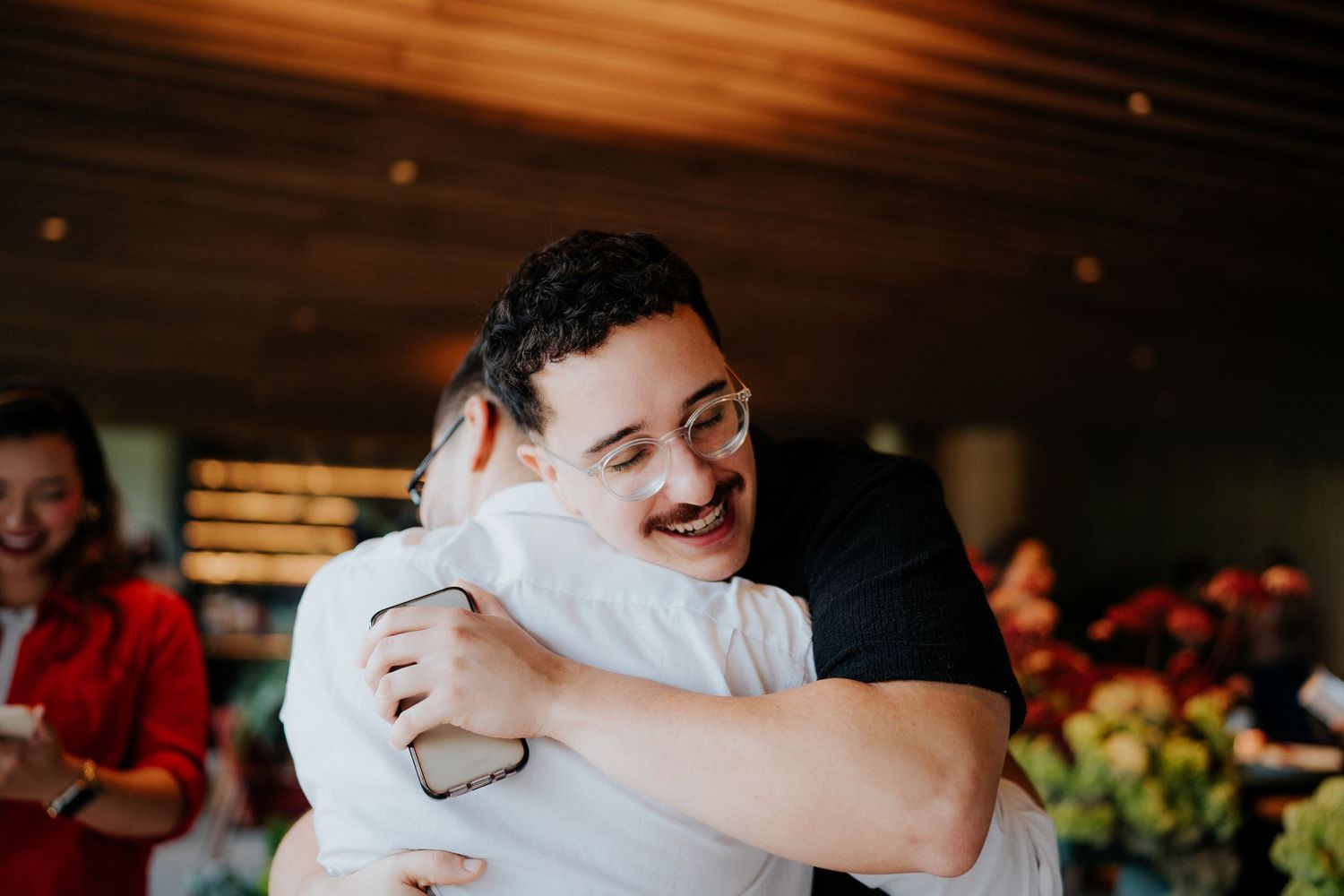 People sharing warm embraces and celebrating during an indoor event.