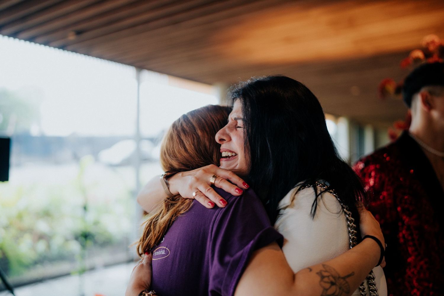 People sharing emotional hugs and embraces during a heartfelt indoor celebration.