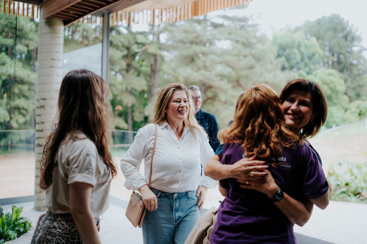 Group of friends laughing and embracing during outdoor gathering.