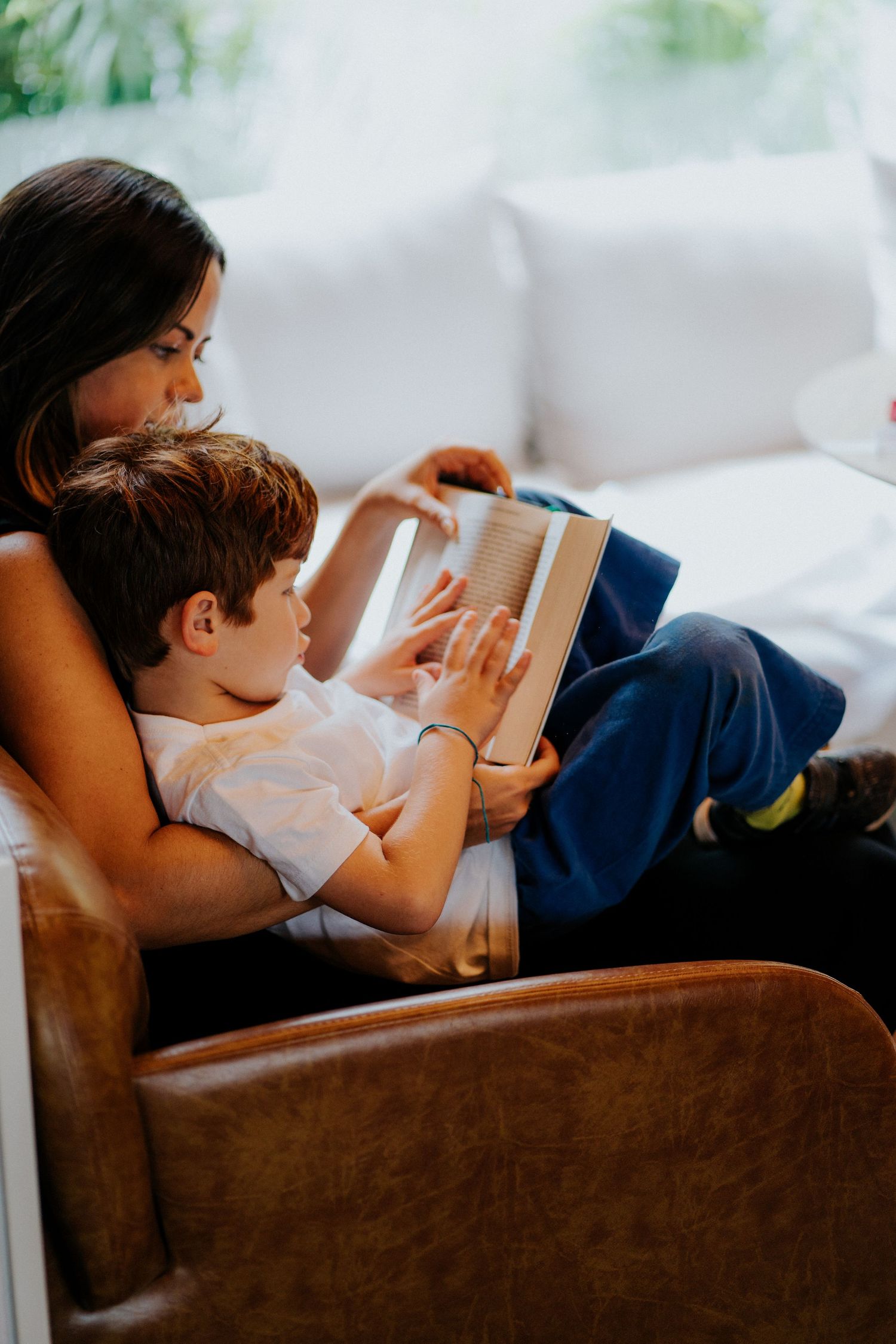 A relaxed reading session on a brown couch with books in hand.