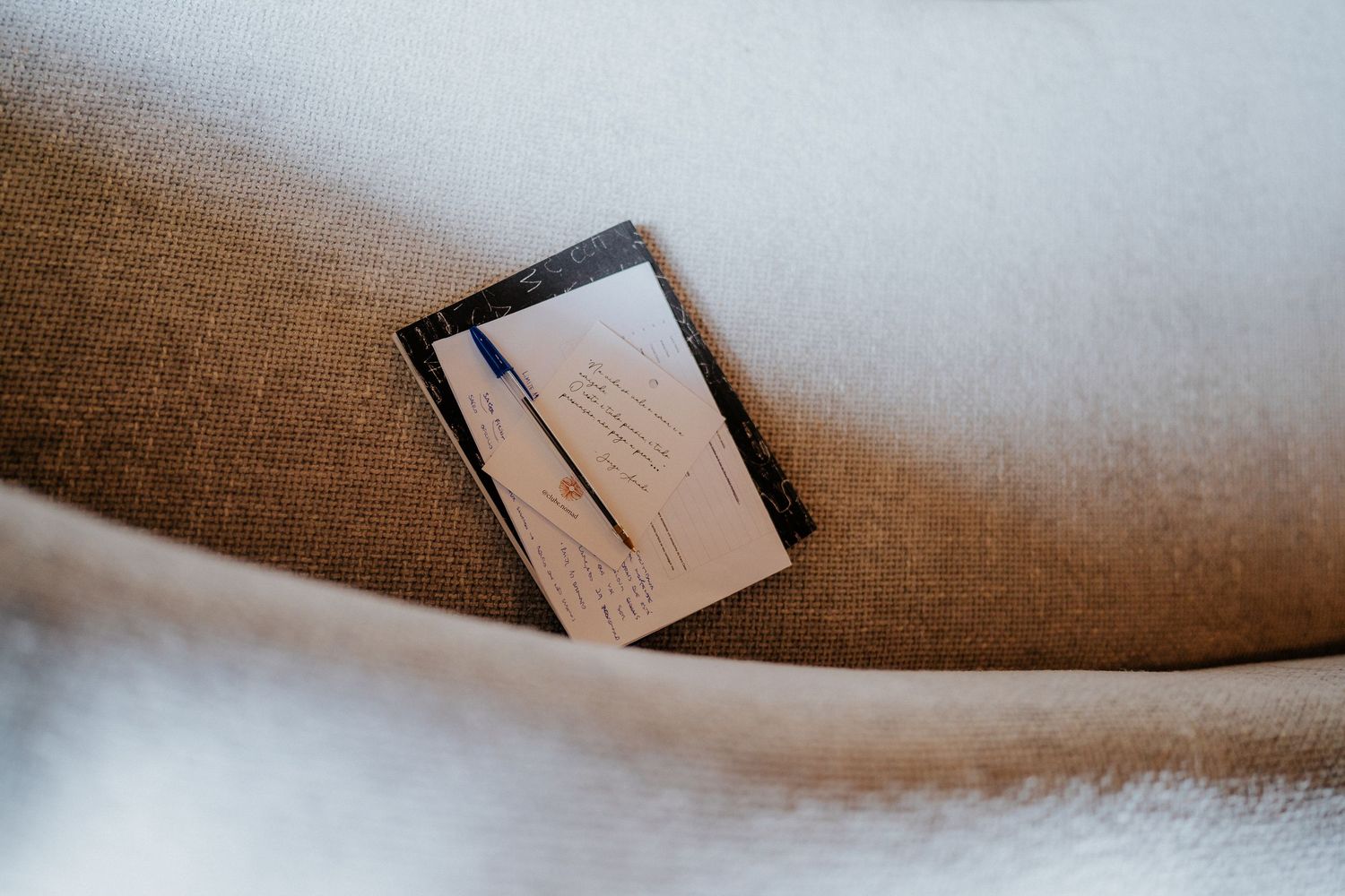Close-up of a beige textured surface with paper or book edges visible.