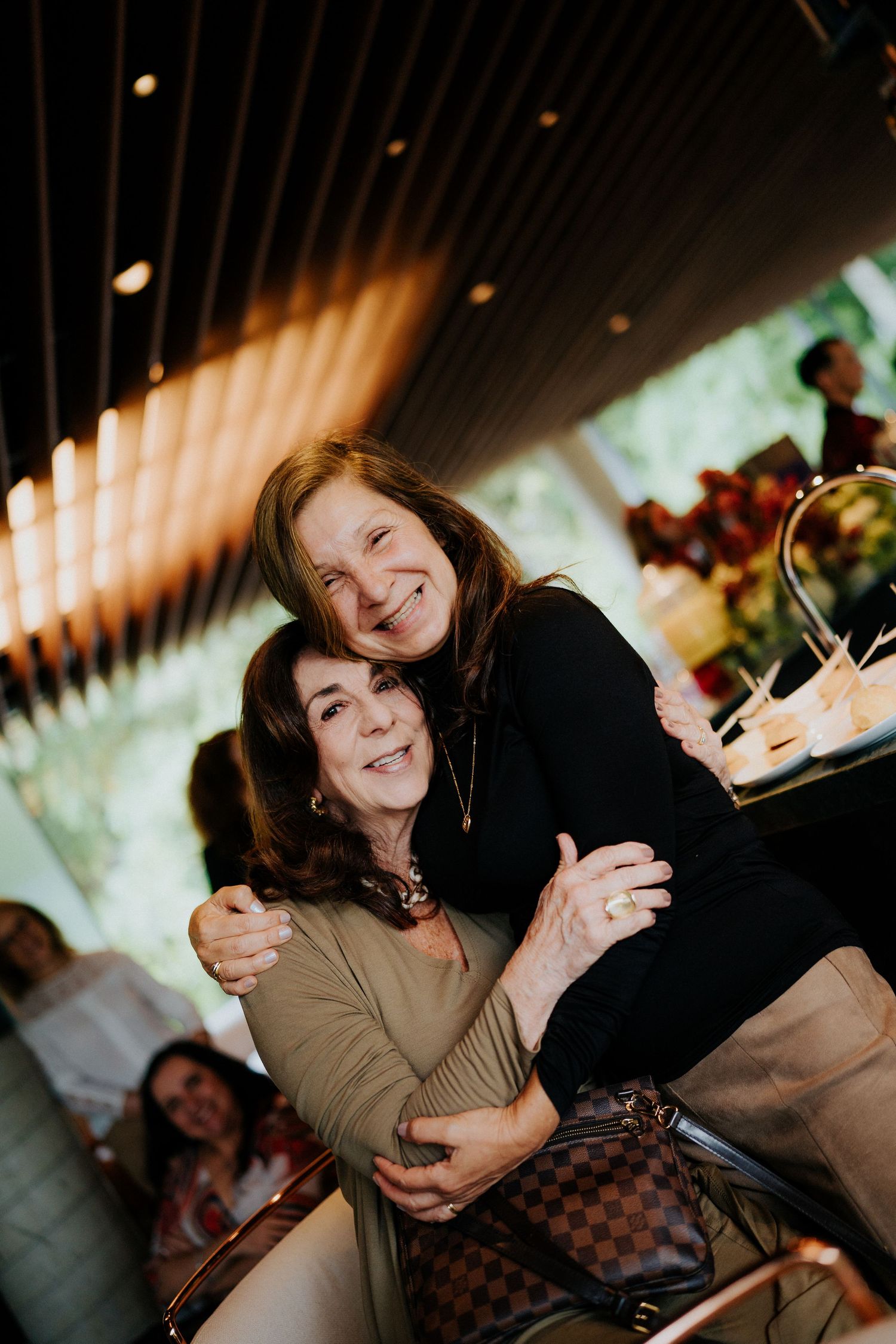 A joyful gathering of friends sharing animated laughter and conversation at a casual indoor event.