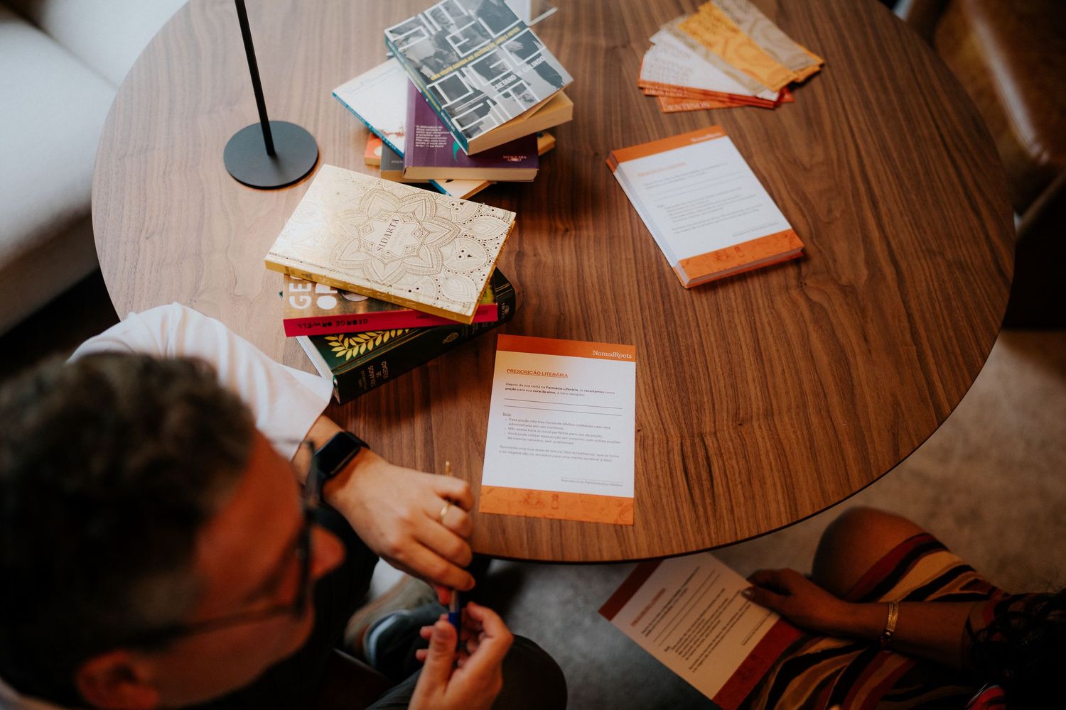 Papers and documents scattered across a wooden table surface during a gathering.