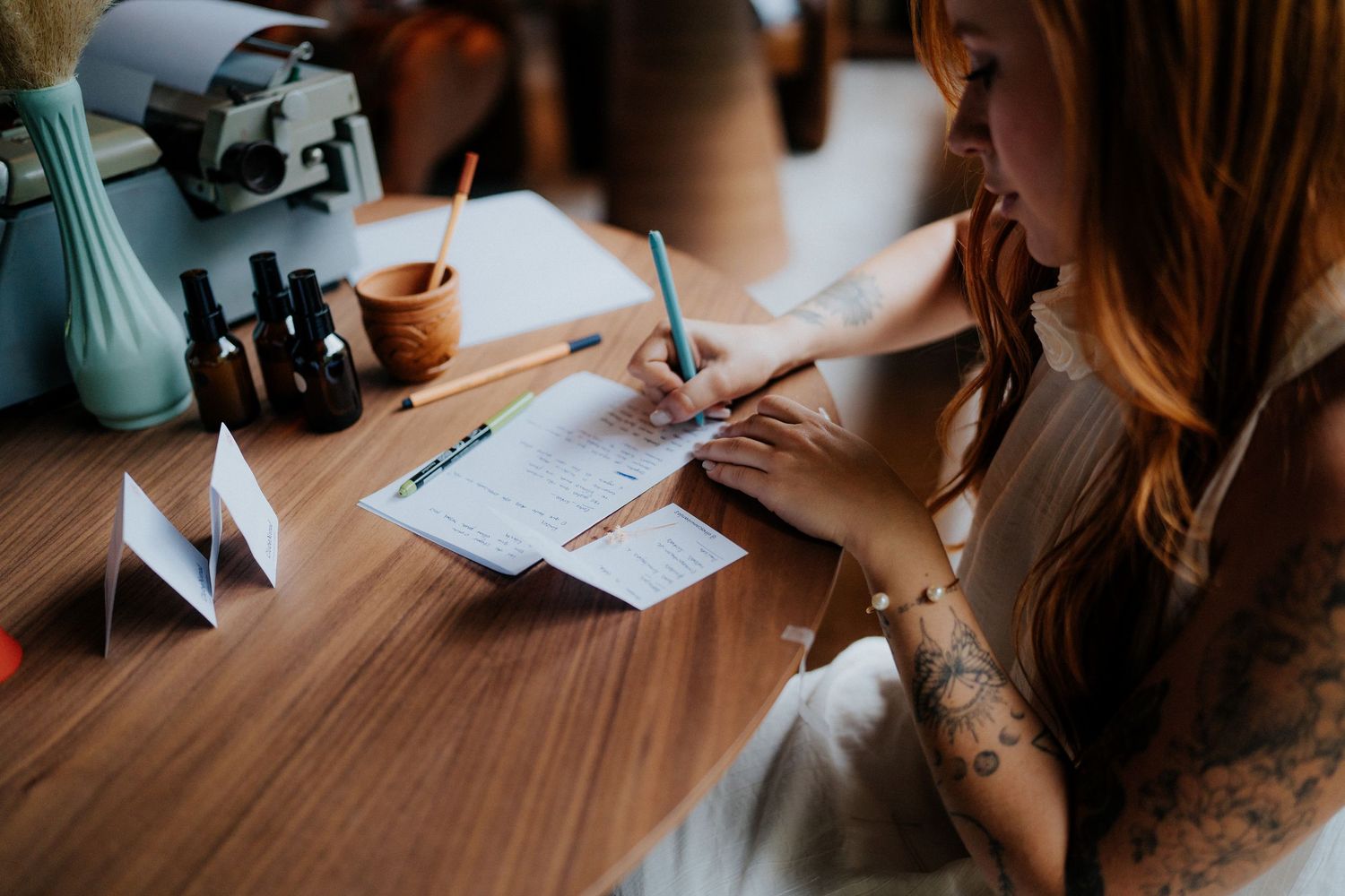 Writing materials and documents spread out on a wooden table during a casual meeting.