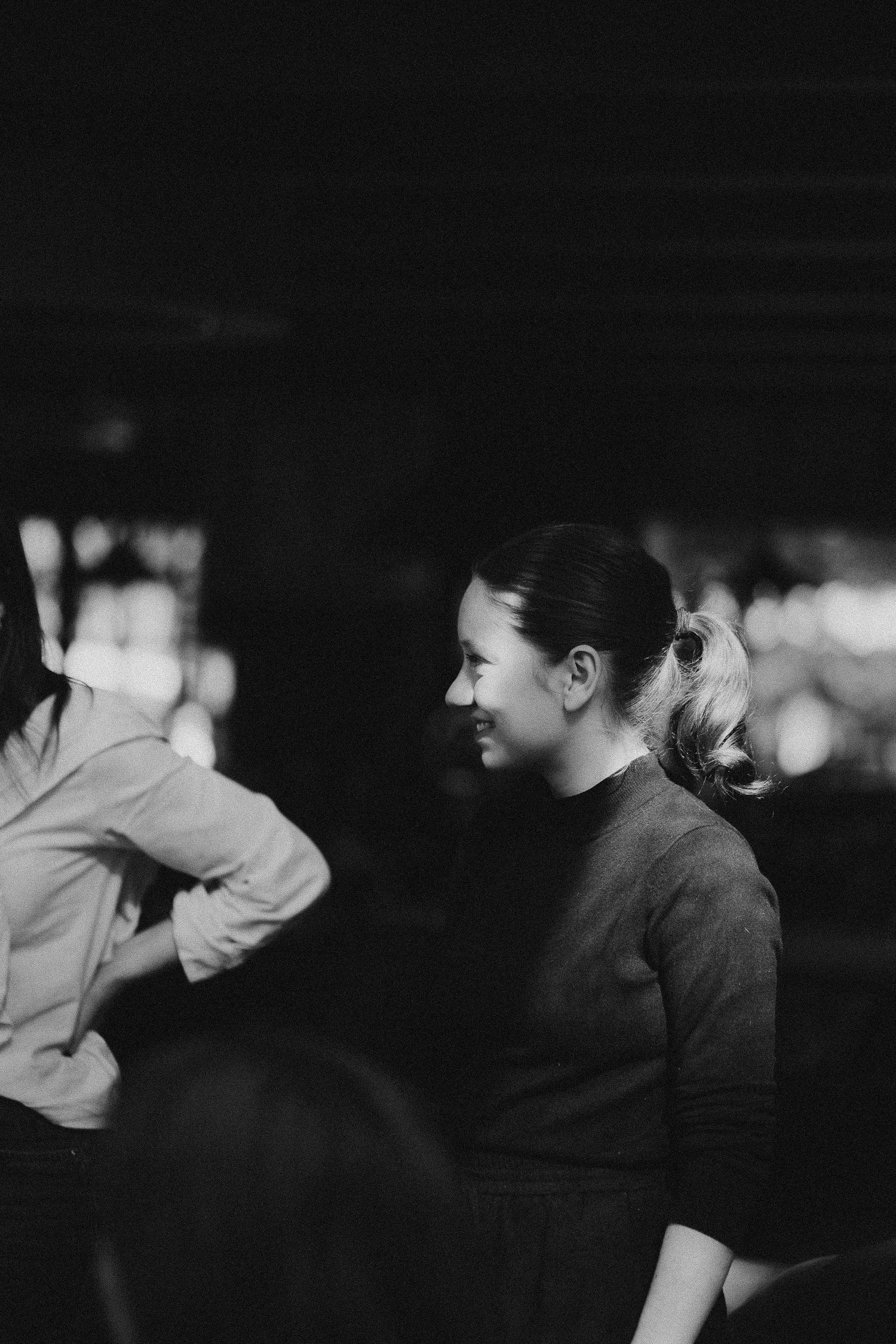 Black and white candid photo showing an intimate group discussion in low light.
