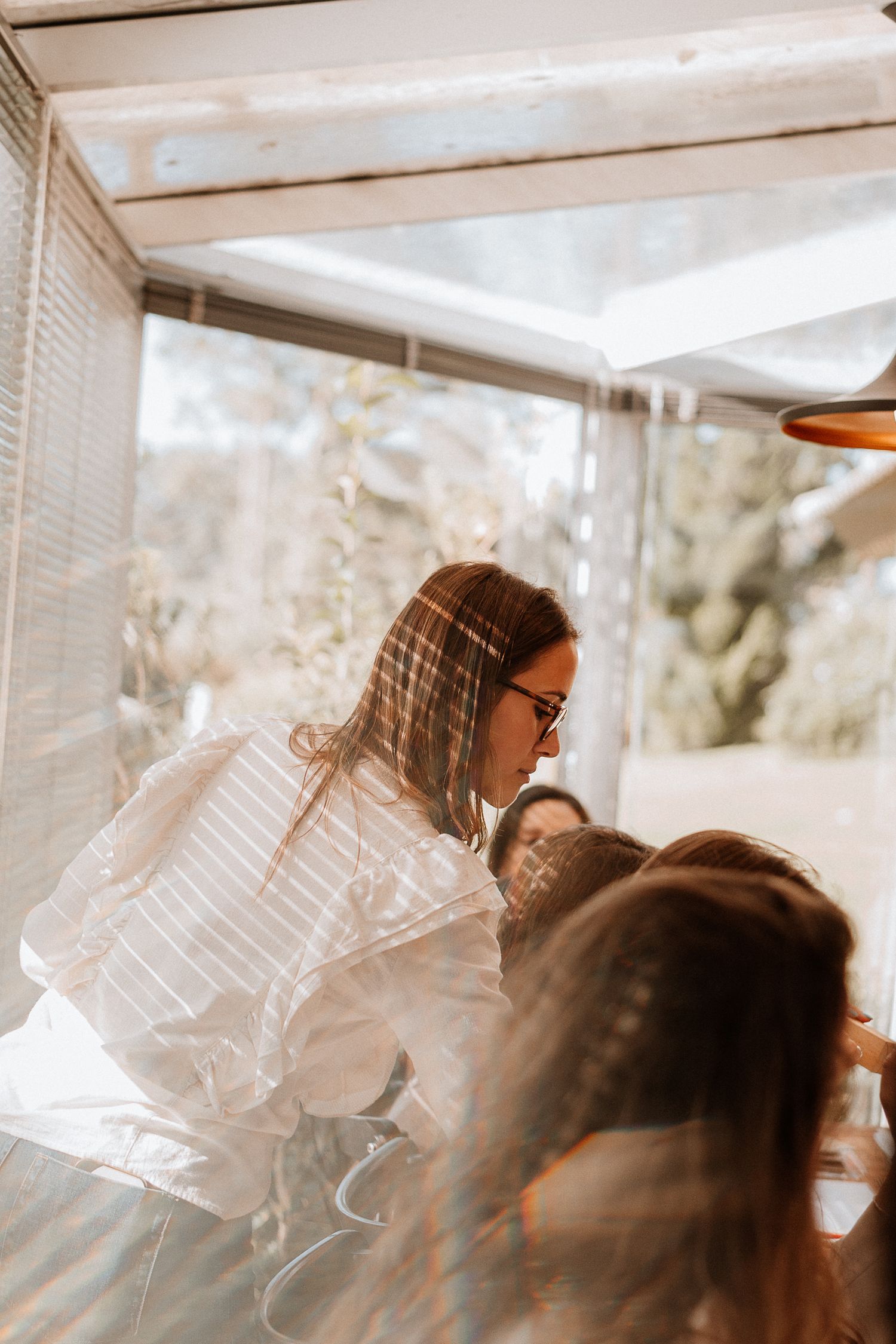 Soft focus photo of people gathered in a sunlit room with windows.