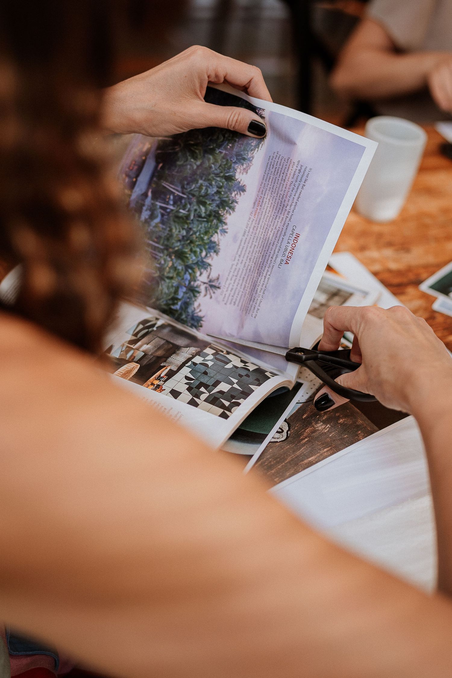 Hands flipping through pages of a photo book or album on wooden table.