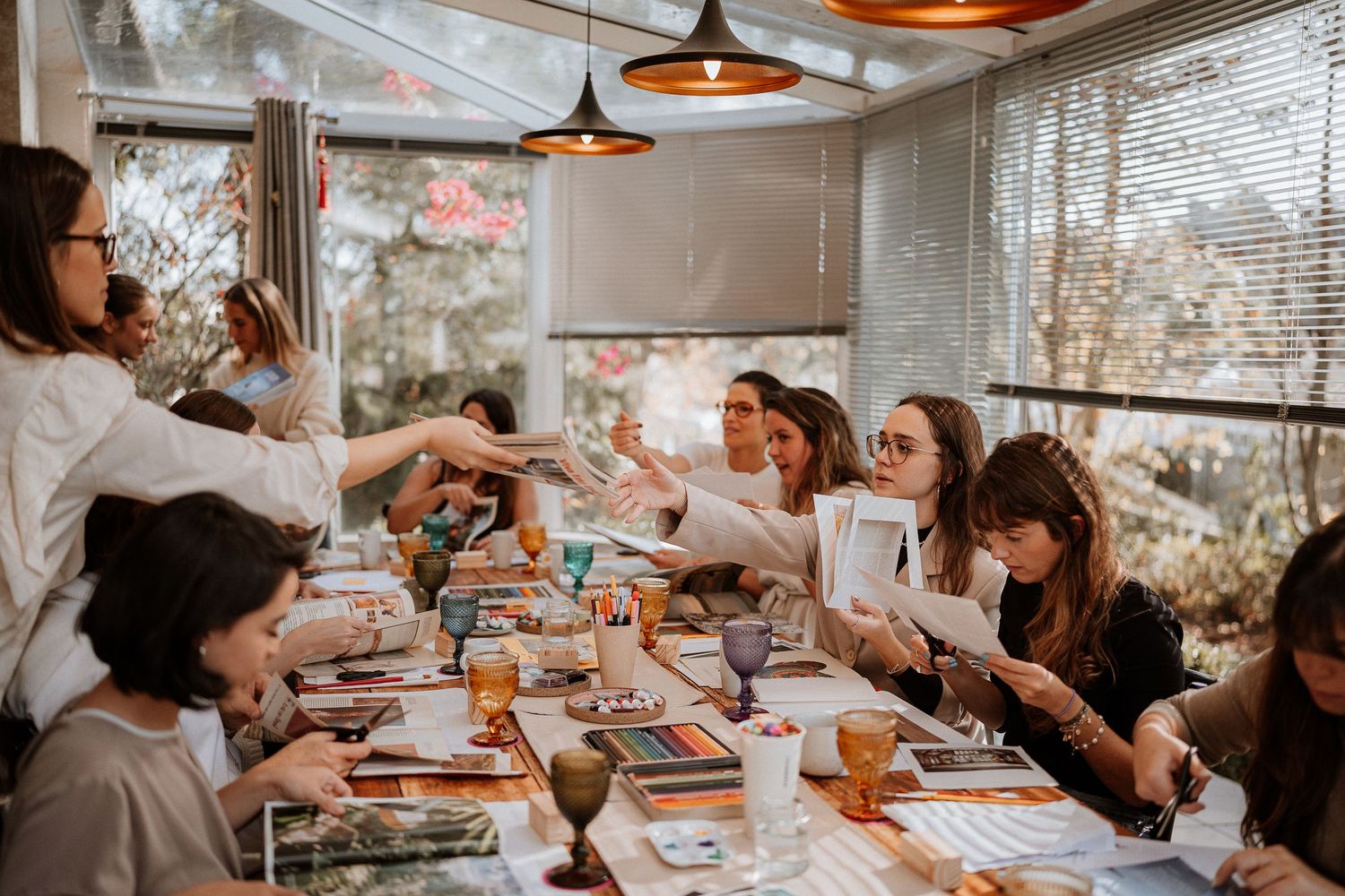 People gathered around a table having drinks and conversation in a bright restaurant setting.