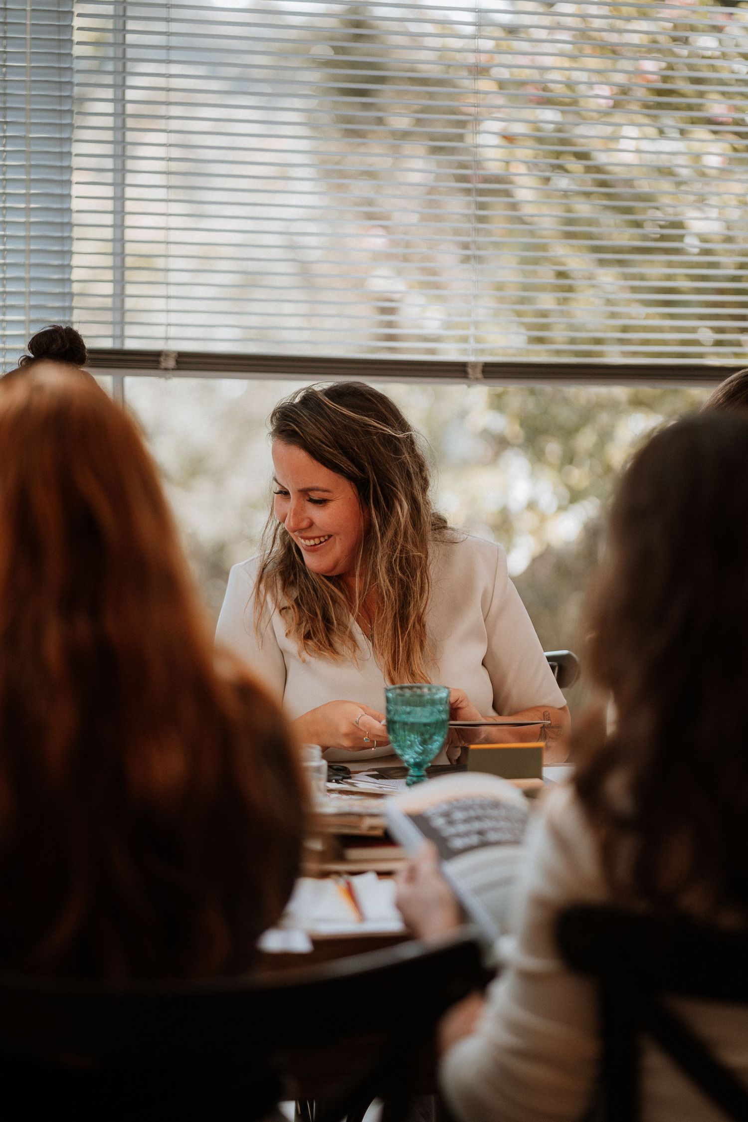 People engaged in discussion around a table in a bright windowed room.