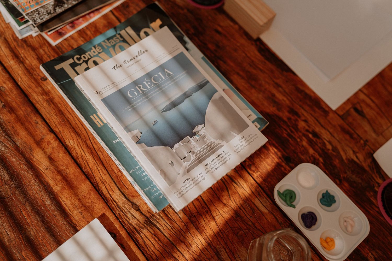 Magazine or brochure lying on wooden surface with watercolor palette nearby.