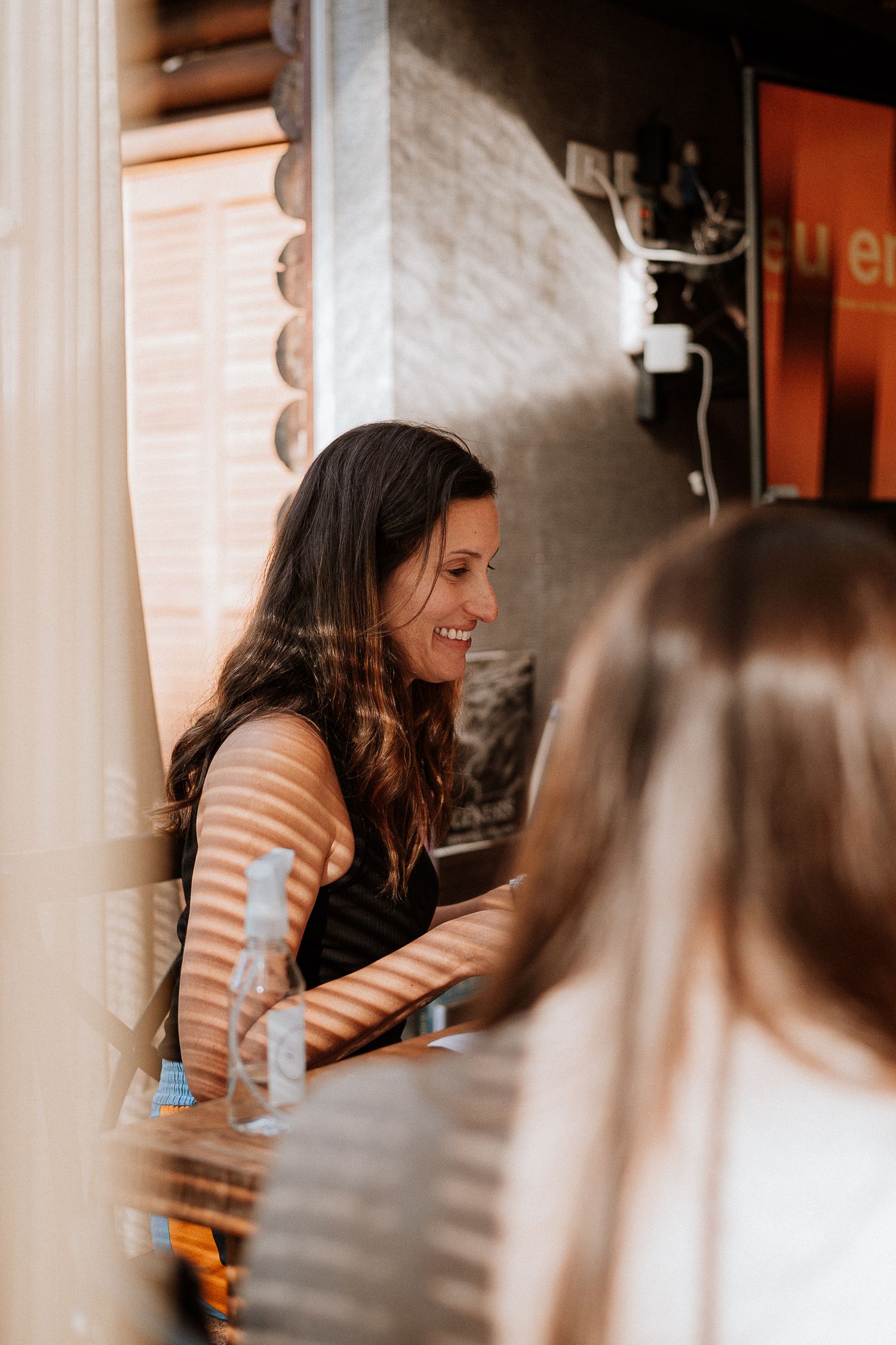 Woman smiling during conversation in a casual indoor setting.
