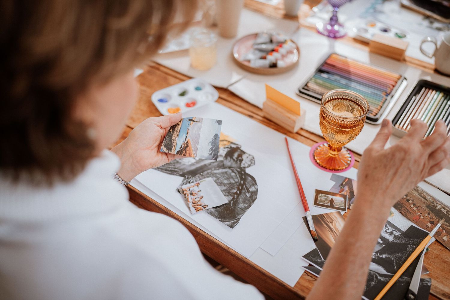 Close-up of watercolor painting materials and sketches on a wooden table.